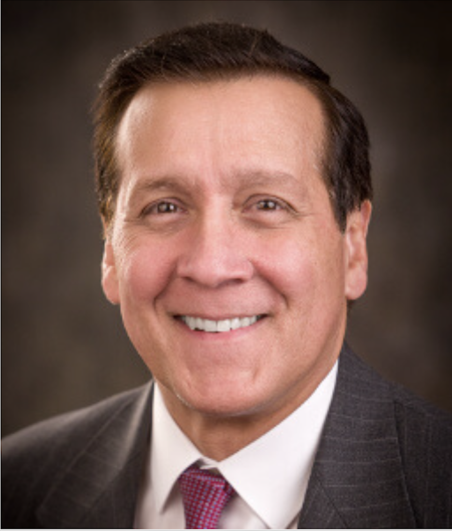 Professional headshot of a smiling man in a suit and tie.