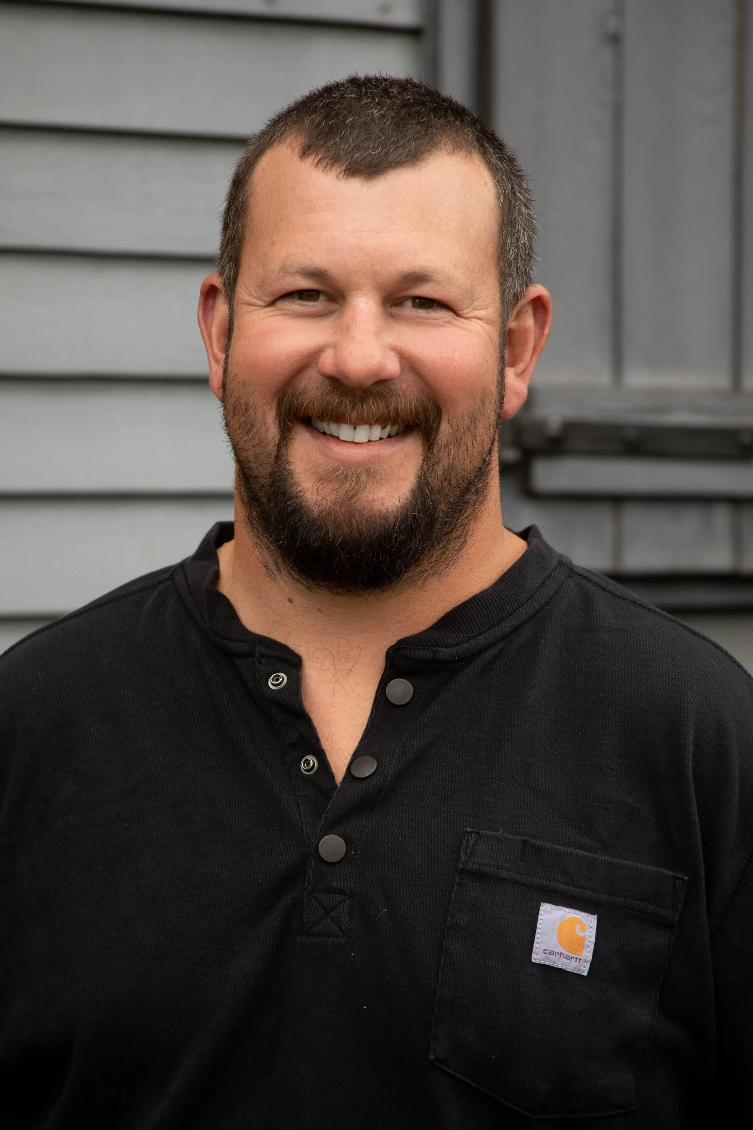 Man smiling in a black shirt with a logo