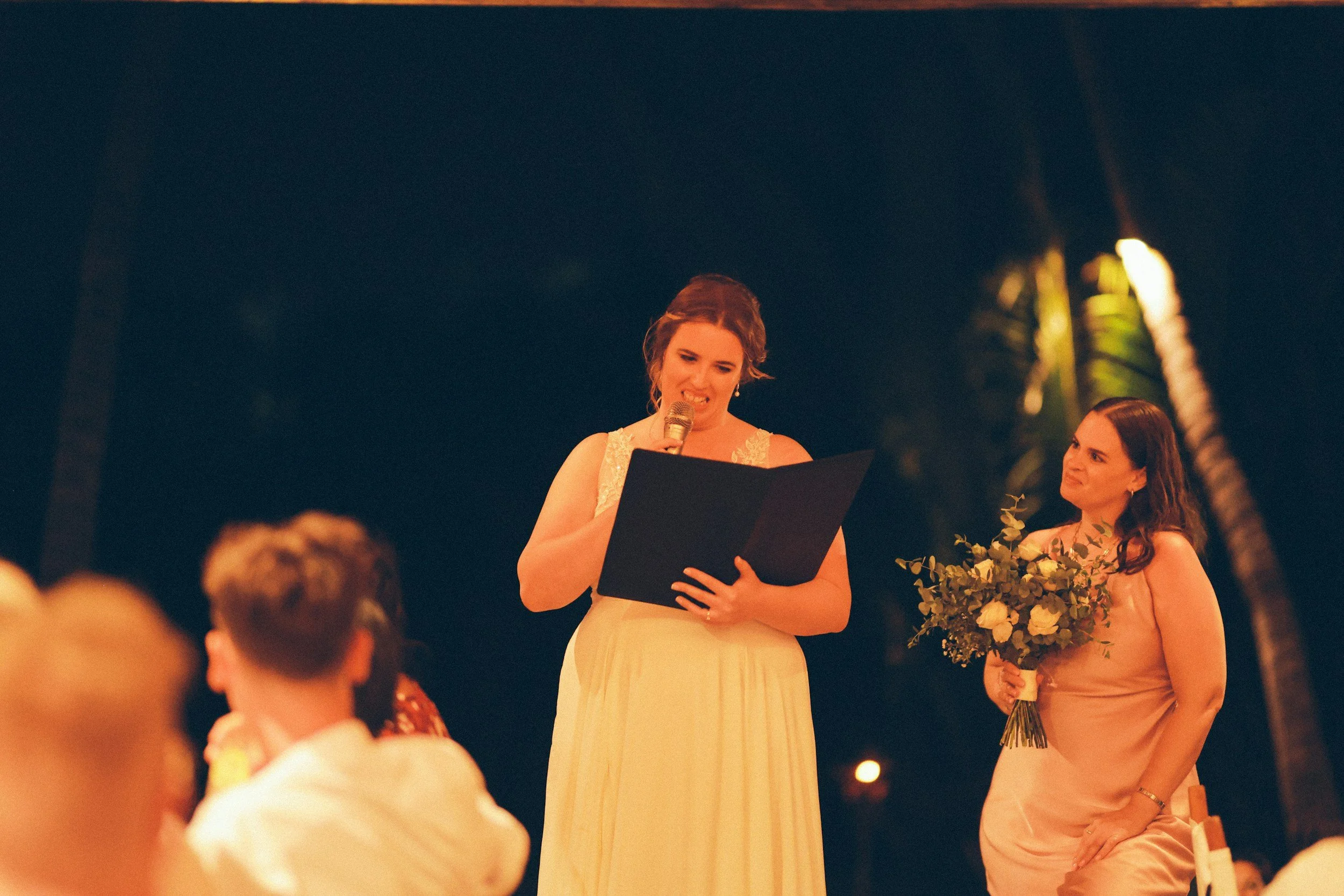 Maid of honor giving a heartfelt wedding speech during the reception while holding a microphone