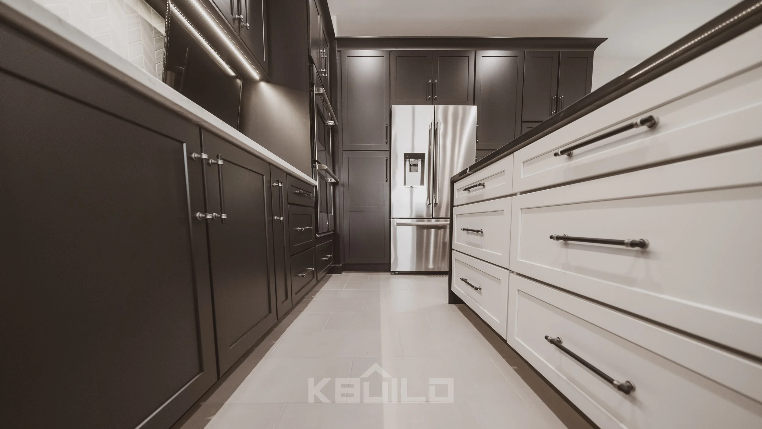 Kitchen remodel with white tile flooring, black cabinets and white countertops, a black marble kitchen island and stainless steel appliances