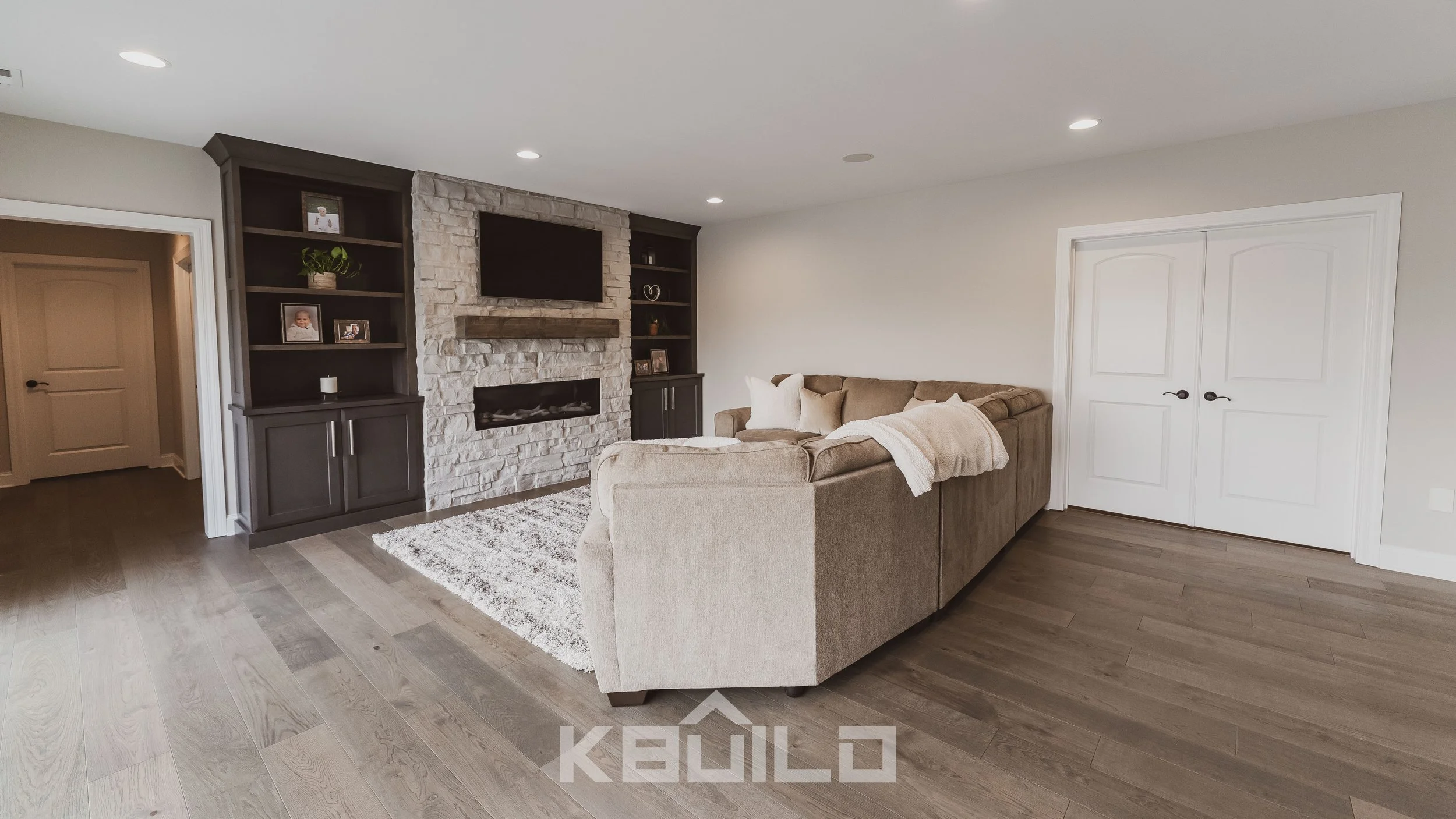 St. Louis basement remodel with large sofa in front of a stone fireplace with built-in book shelves