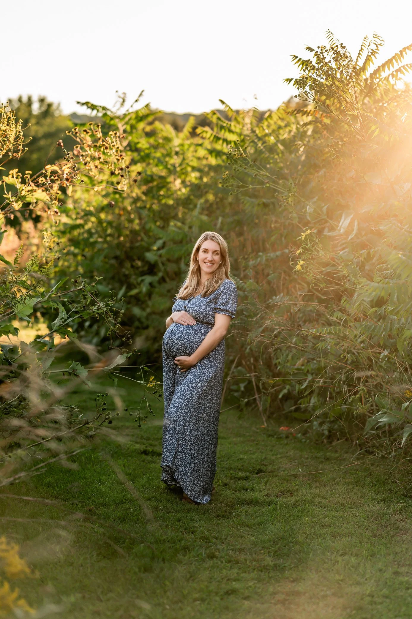 A pregnant woman poses for a maternity photo in tall grass in West Hartford Connecticut