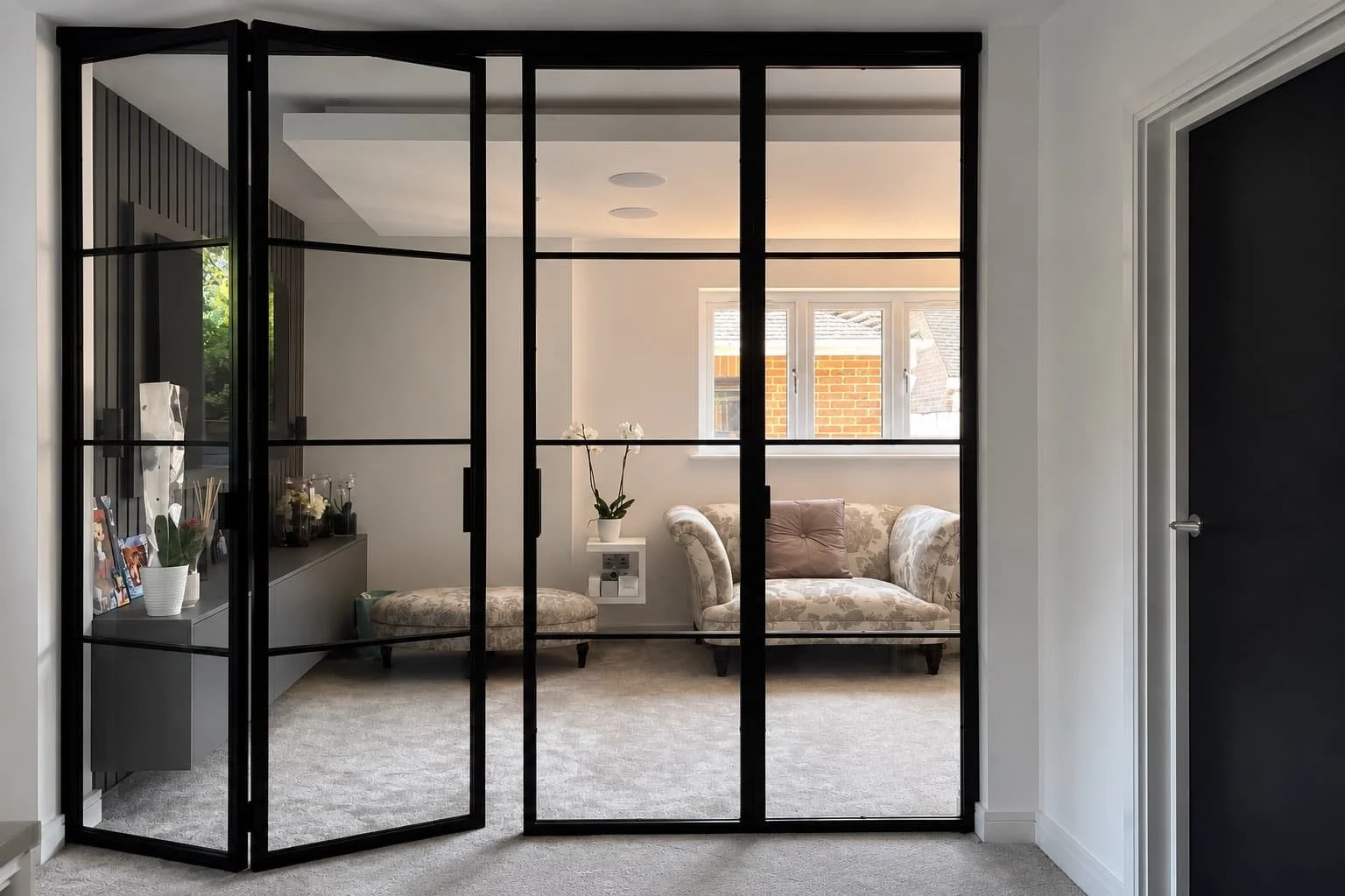 Bespoke steel internal bi-folding door panels folding open within a luxury residential interior by Joshua James.