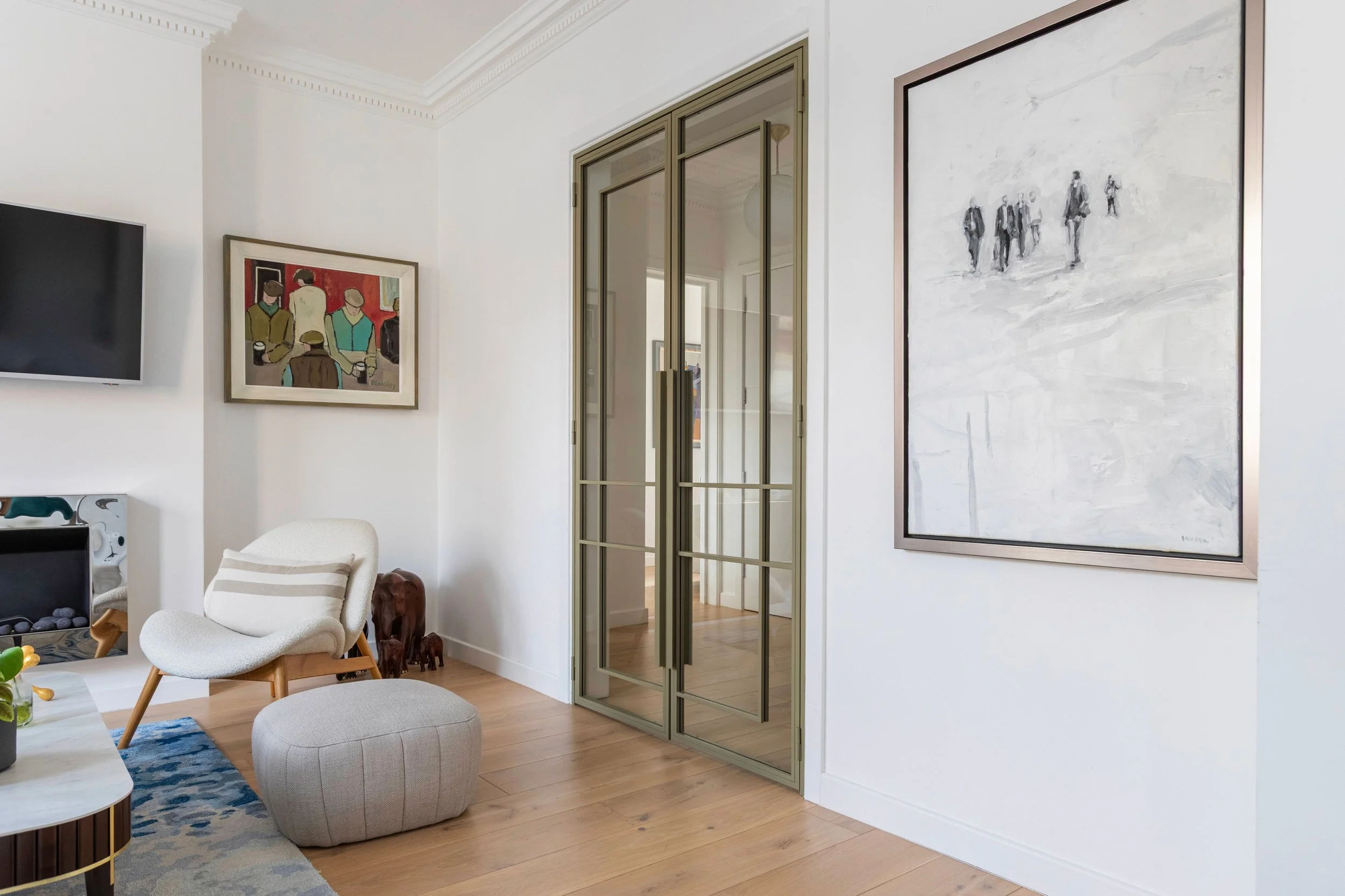 Olive grey double steel doors with clear glass panels separating living room and hallway in Chelsea apartment.