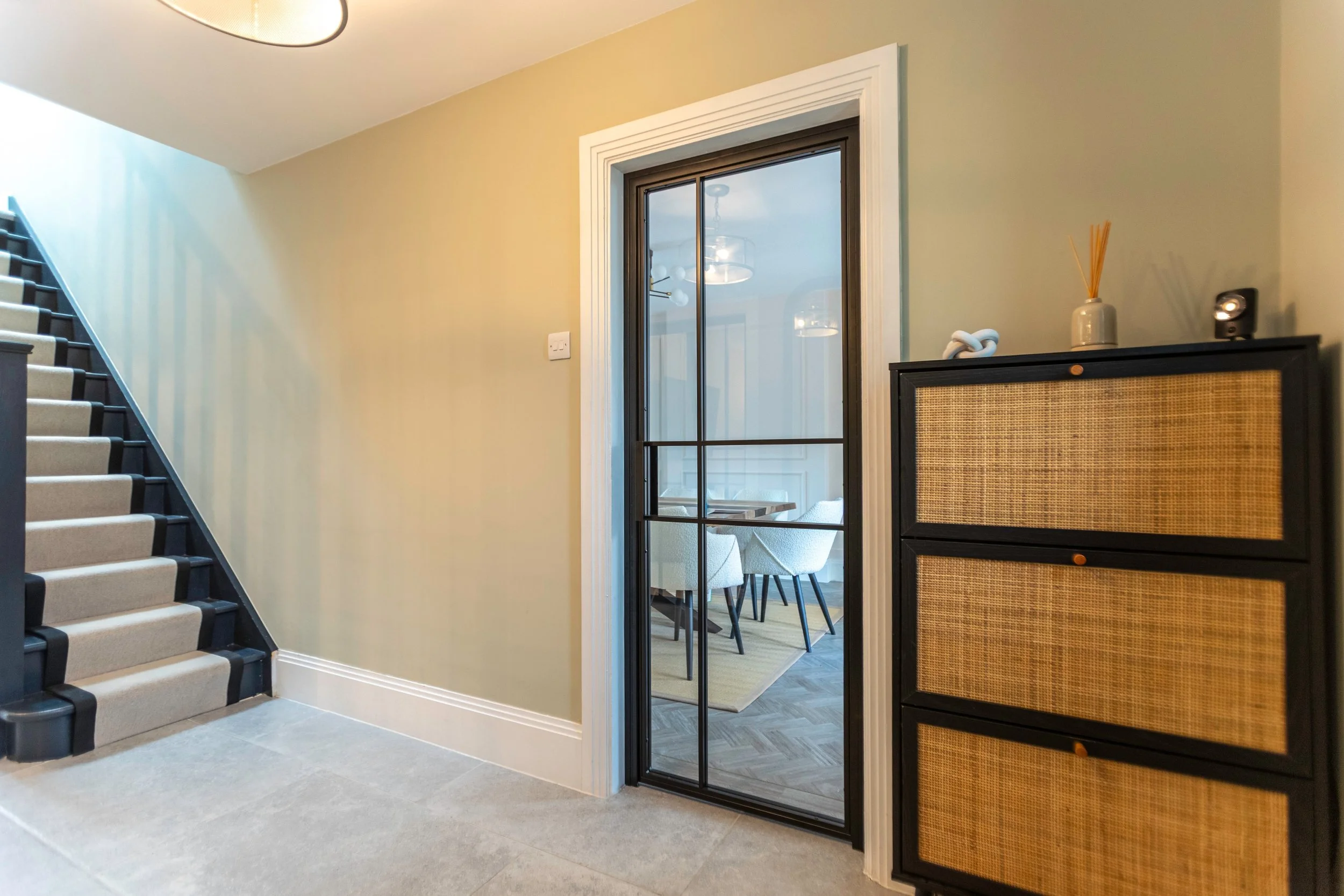 Bespoke steel internal doors in a residential hallway showing light flowing from an adjoining room by Joshua James.