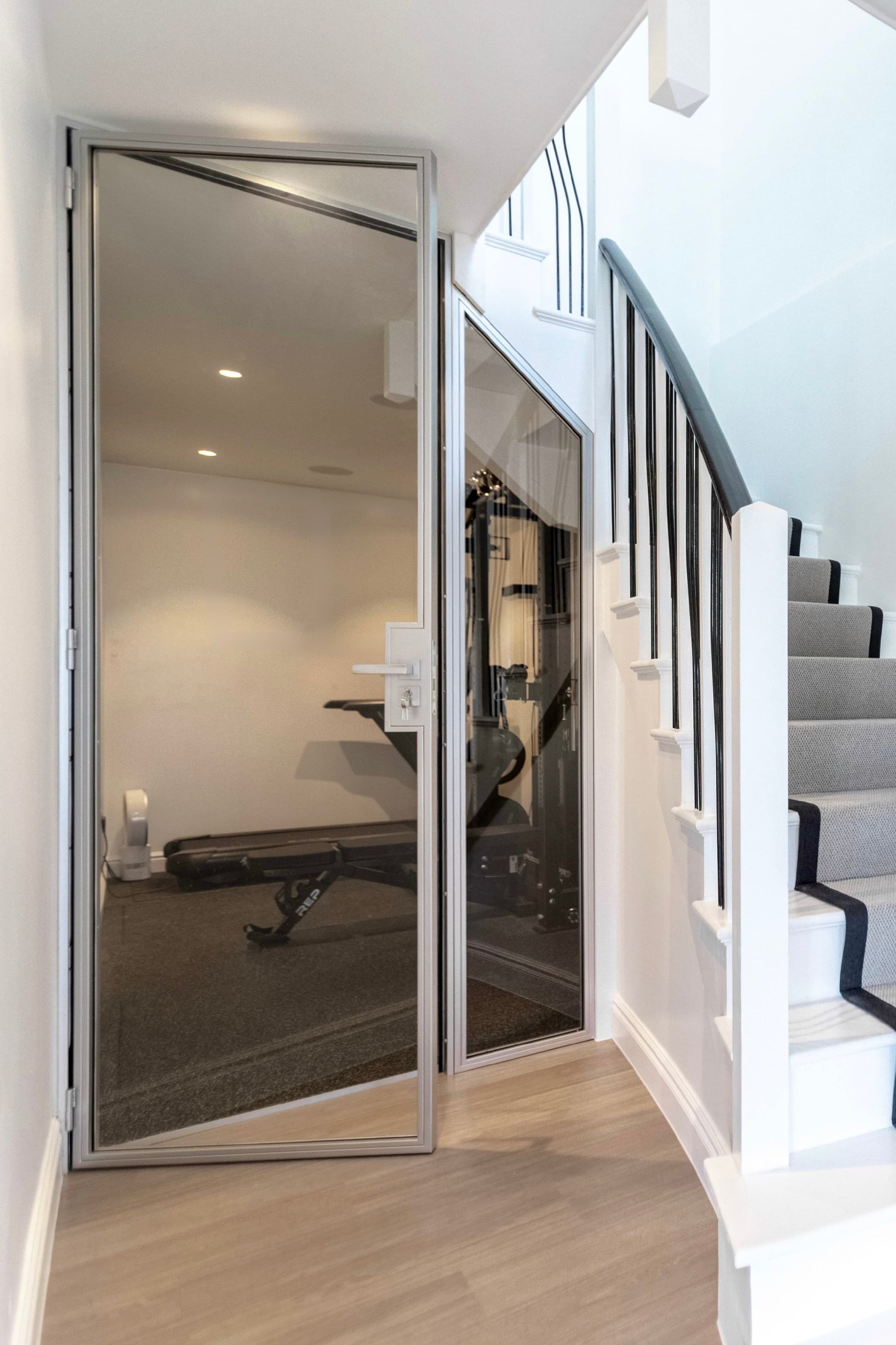 Bespoke steel glazed sliding door opening to a home gym in a hallway of a residential property in Highgate, London, installed by Joshua James.