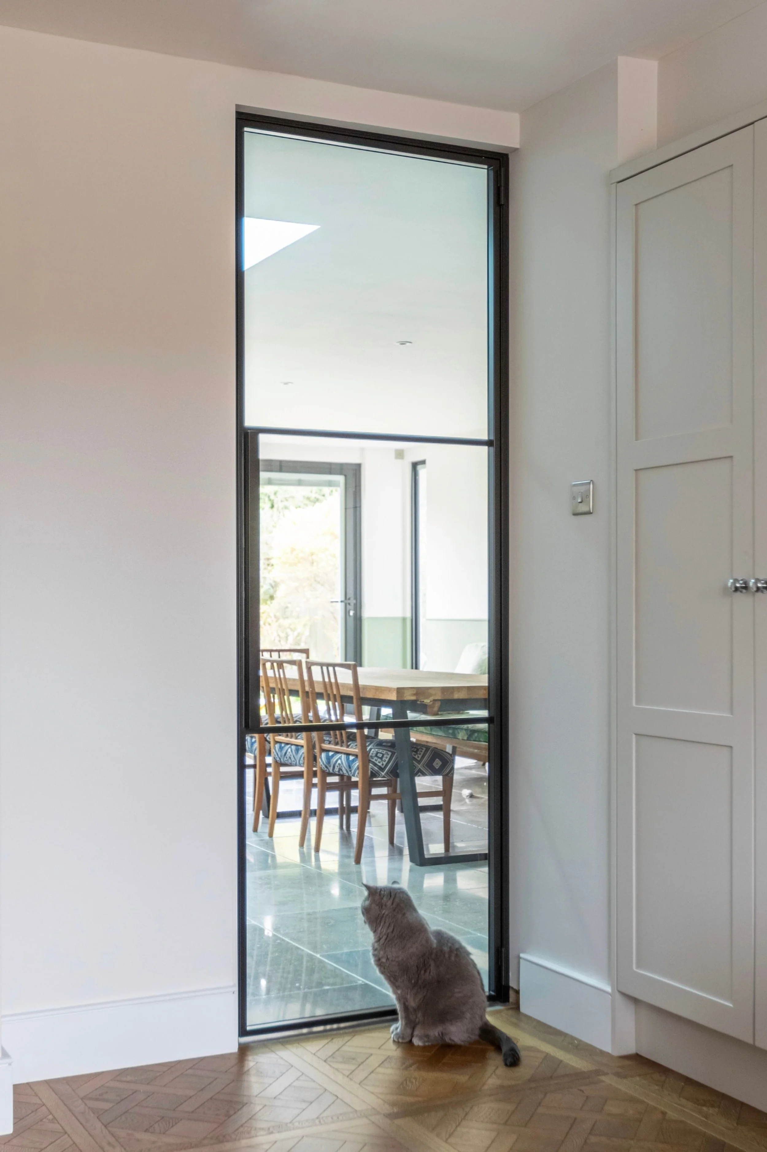 Single internal steel door with two horizontal bars allowing light between living room and kitchen dining in Oxted Surrey.