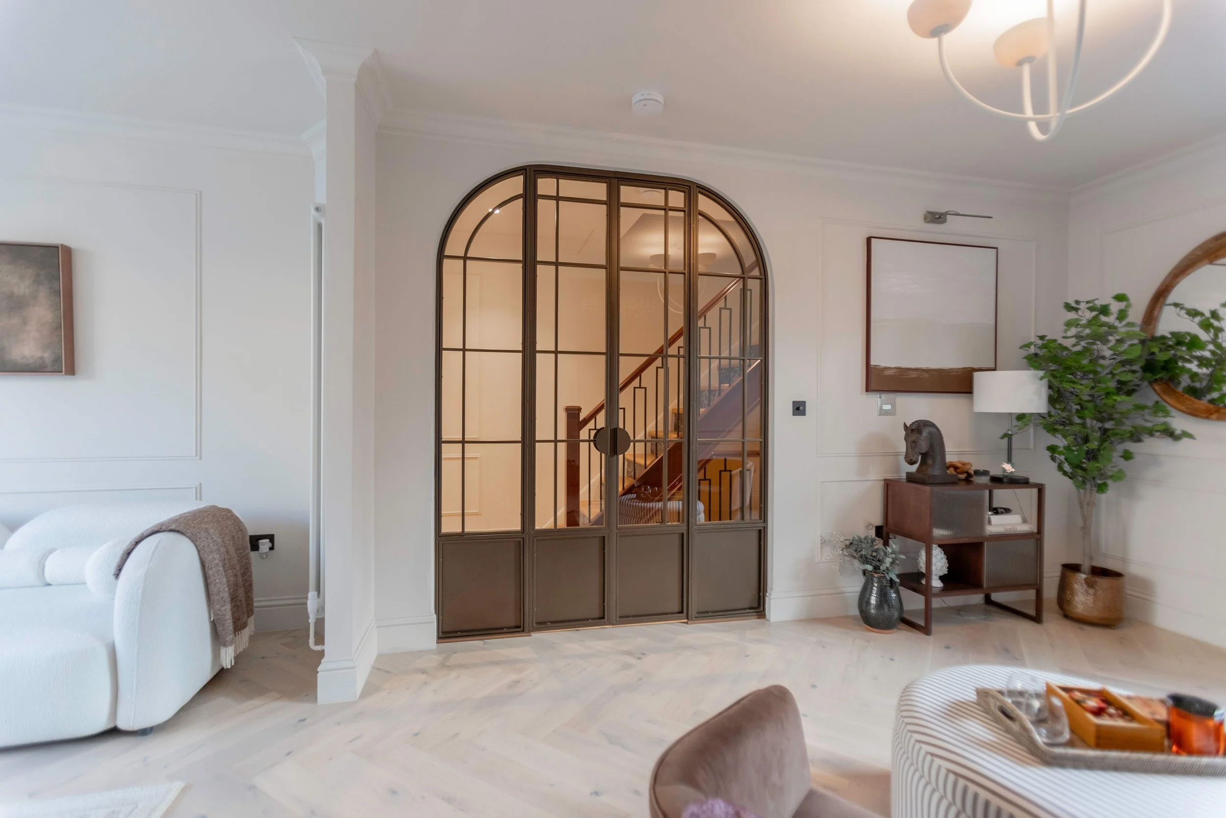 Bronze steel doors with arched screens creating a statement entrance in a Hackney London home.
