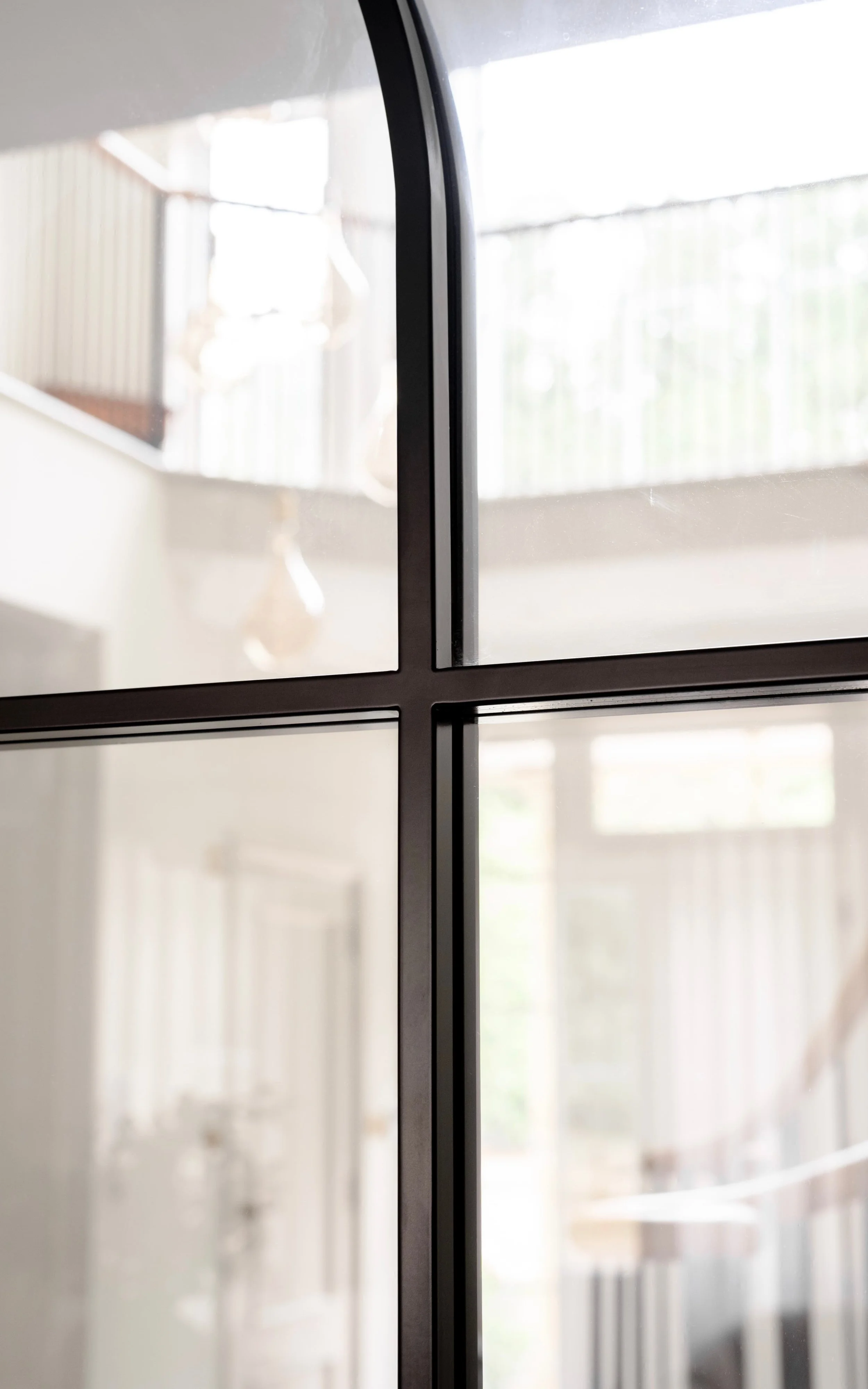 Close-up of a bespoke InoCross20FR arched steel-framed fire-rated door, highlighting the curved steel profile, slim horizontal glazing bars and clear glass.