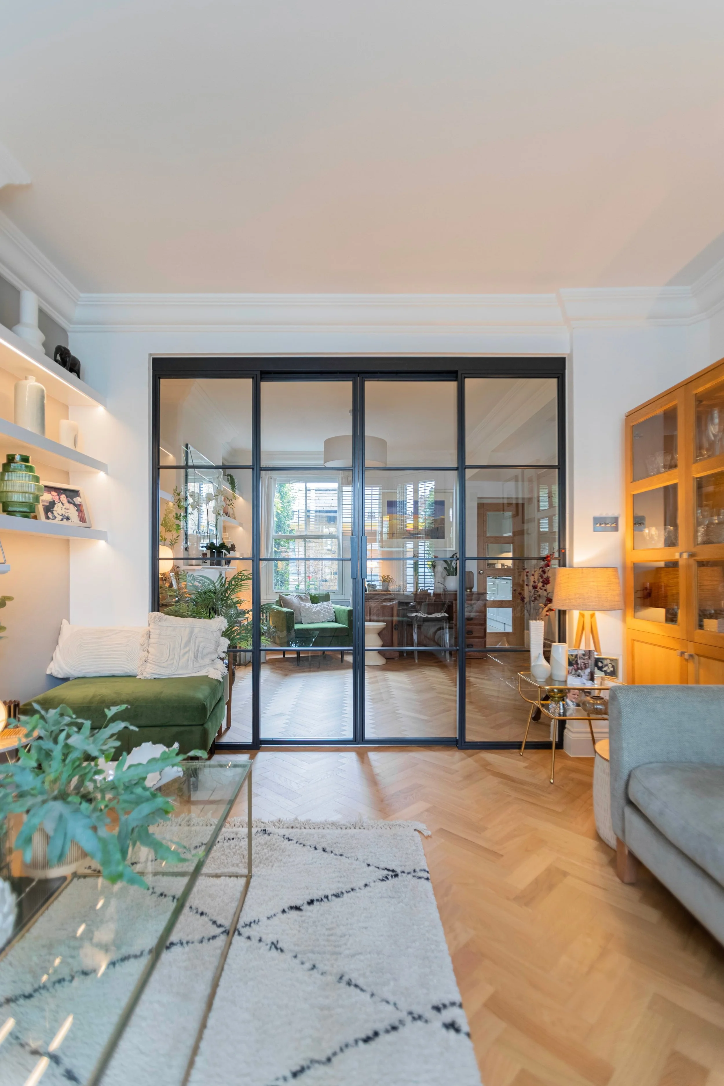 Black steel room divider doors separating two elegant living spaces while allowing natural light to flow throughout the home.