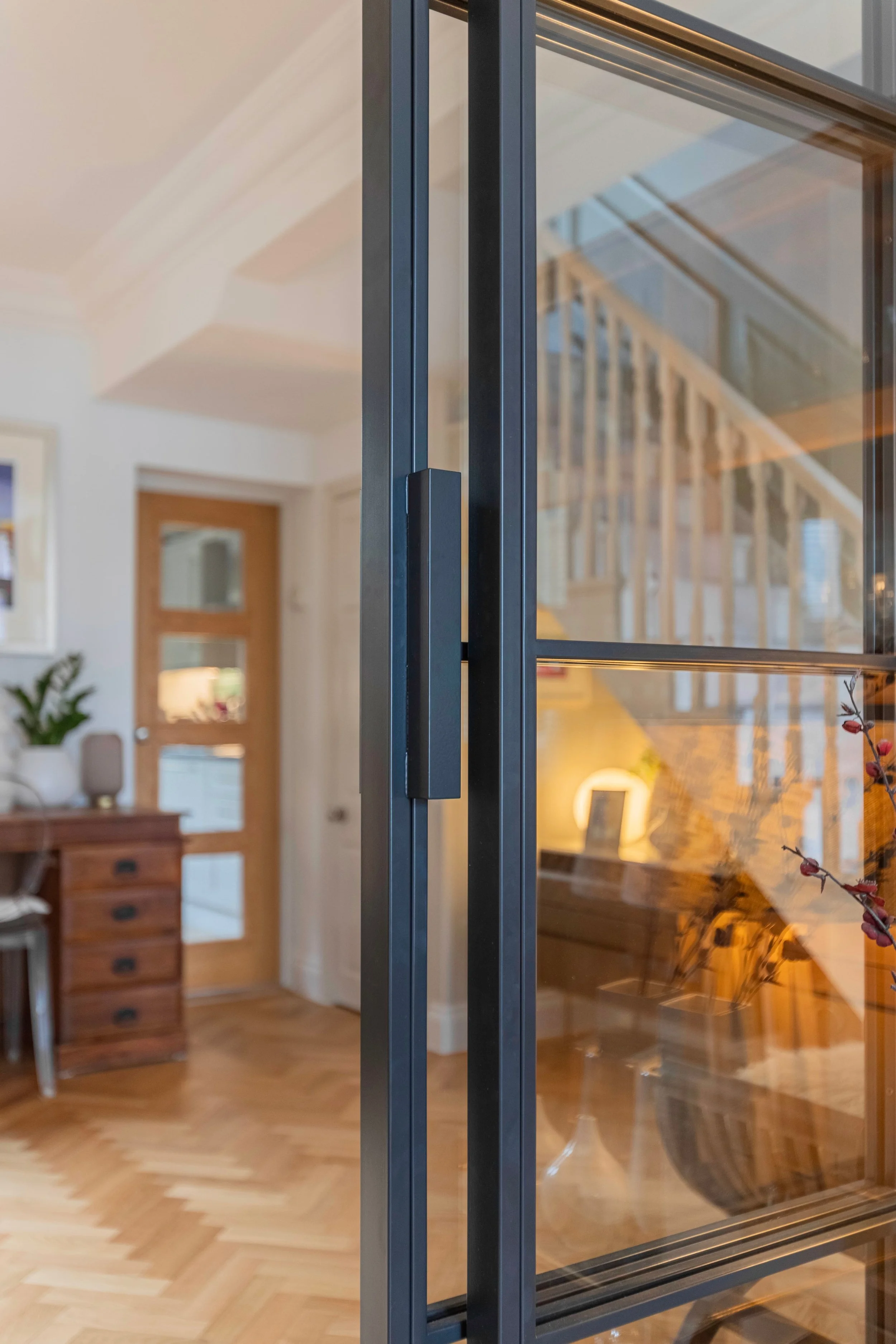 Close-up of a minimalist black handle on bespoke internal steel sliding doors with slim steel framing.