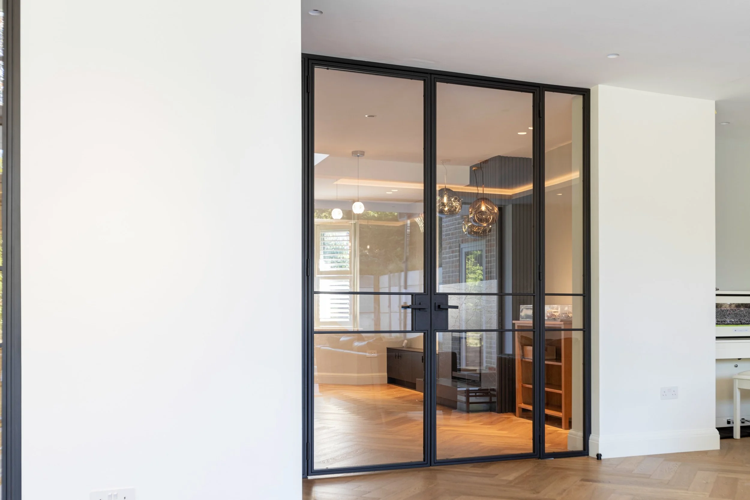 Steel framed doors separating kitchen and living space in a luxury interior.