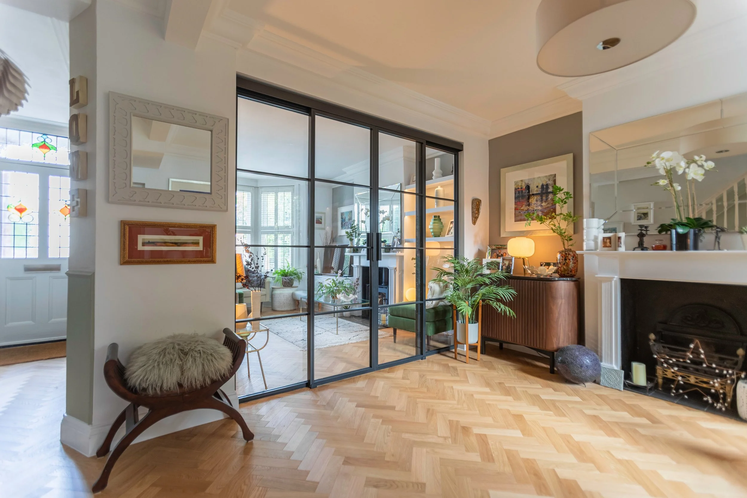 Black steel sliding doors creating an elegant divide between two living spaces in a contemporary Wimbledon home.