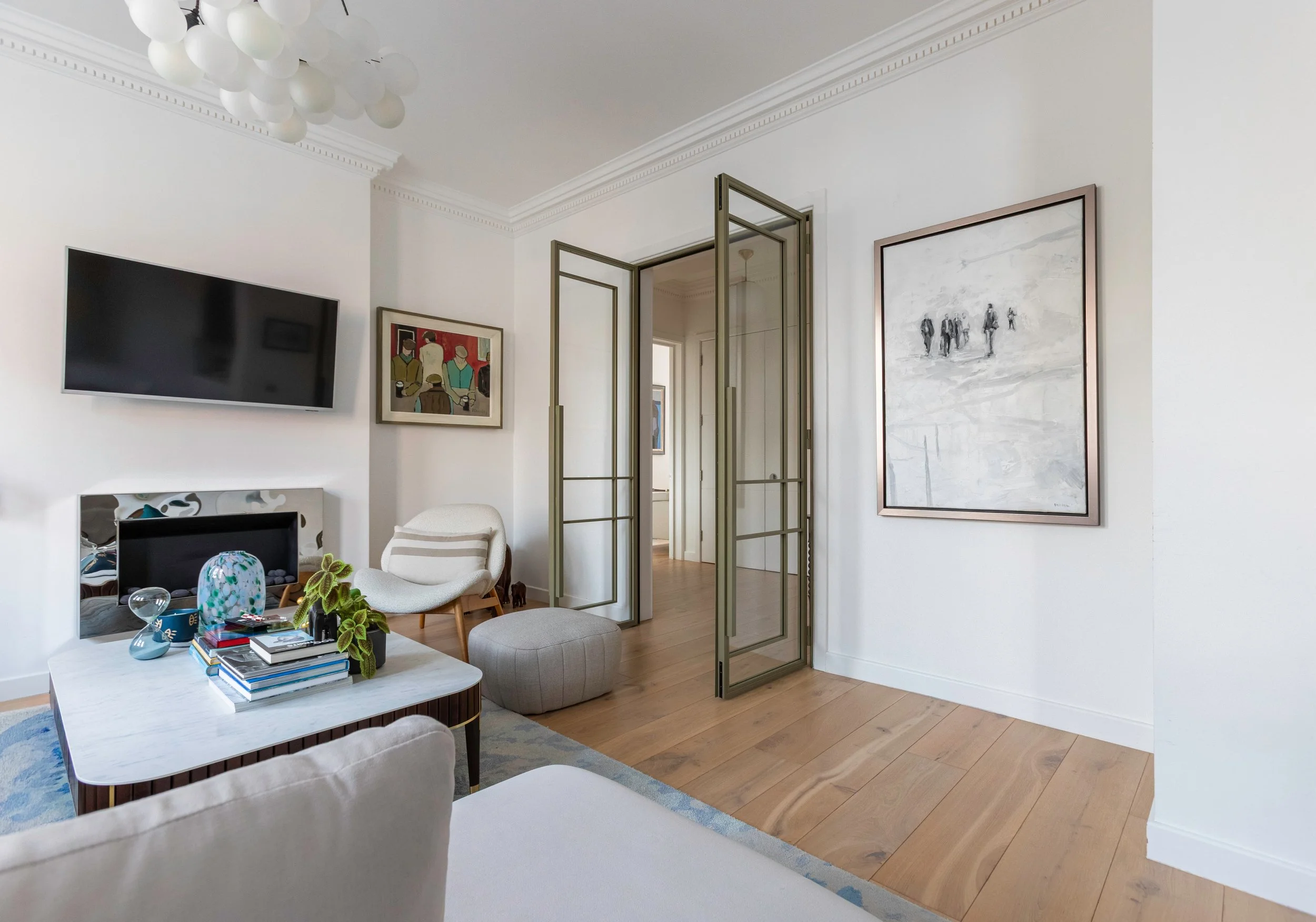 Open double internal steel doors in olive grey creating flow between living room and hallway in Chelsea apartment.