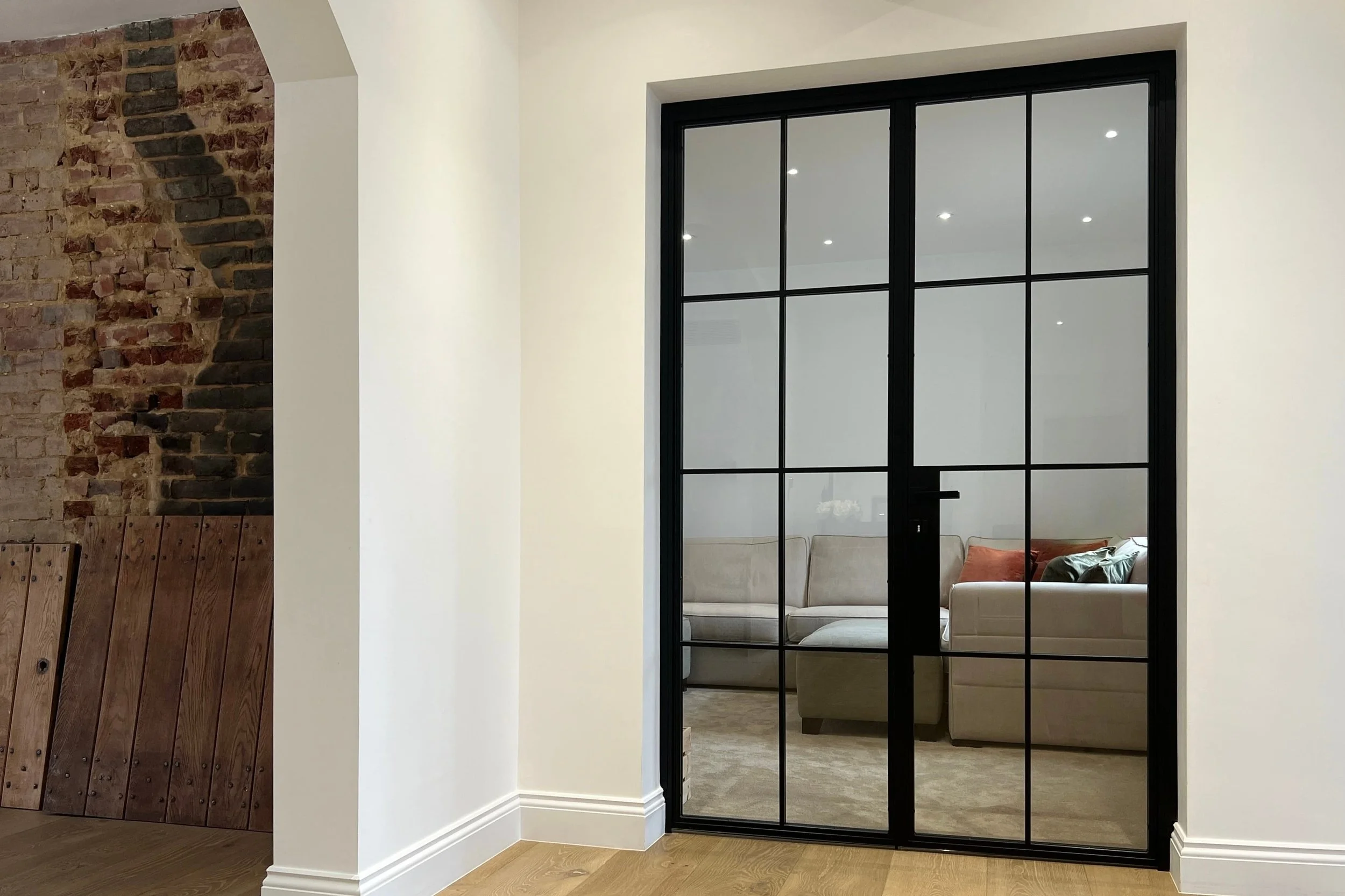 Double internal steel doors between hallway and reception room in a luxury home.