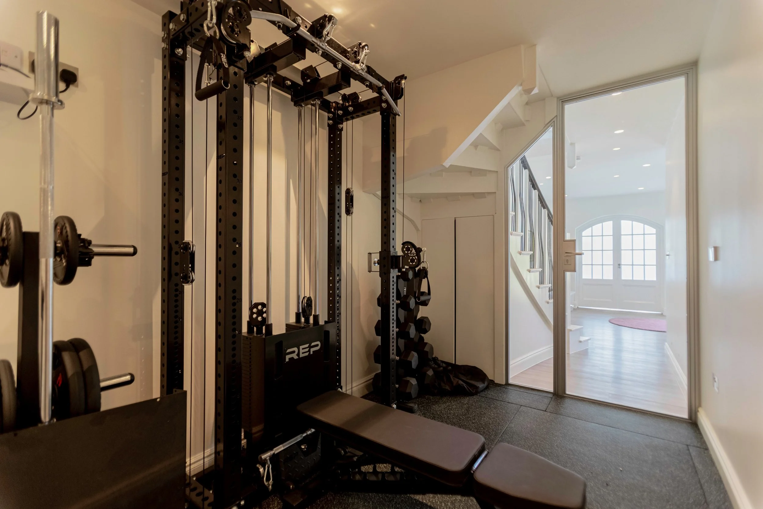 Interior view of a home gym enclosed by a bespoke steel glazed single hinged door, photographed from inside the room in a residential property in Highgate, London, installed by Joshua James.
