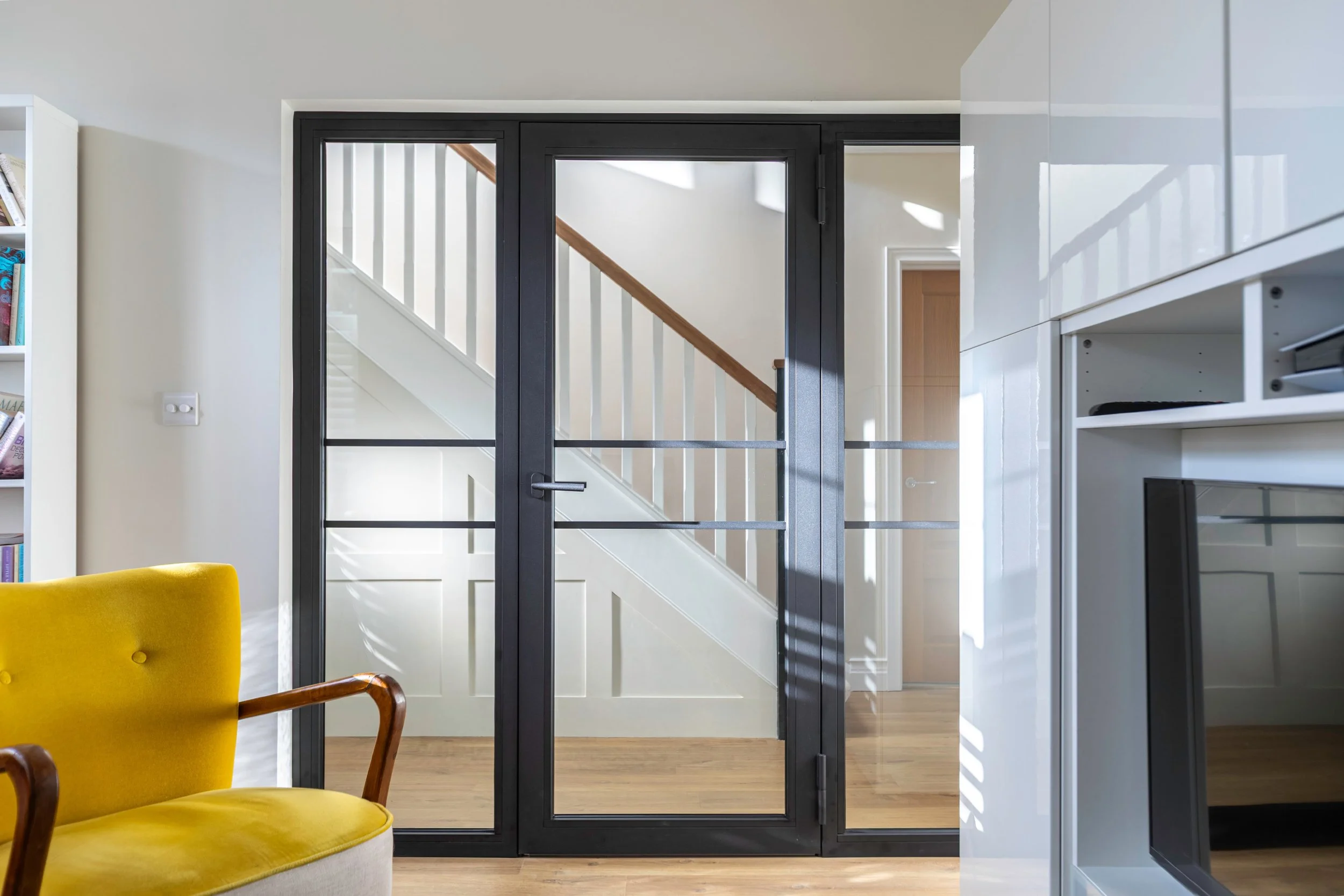 Fire-rated internal steel door with side screens separating hallway and living space in modern UK home.