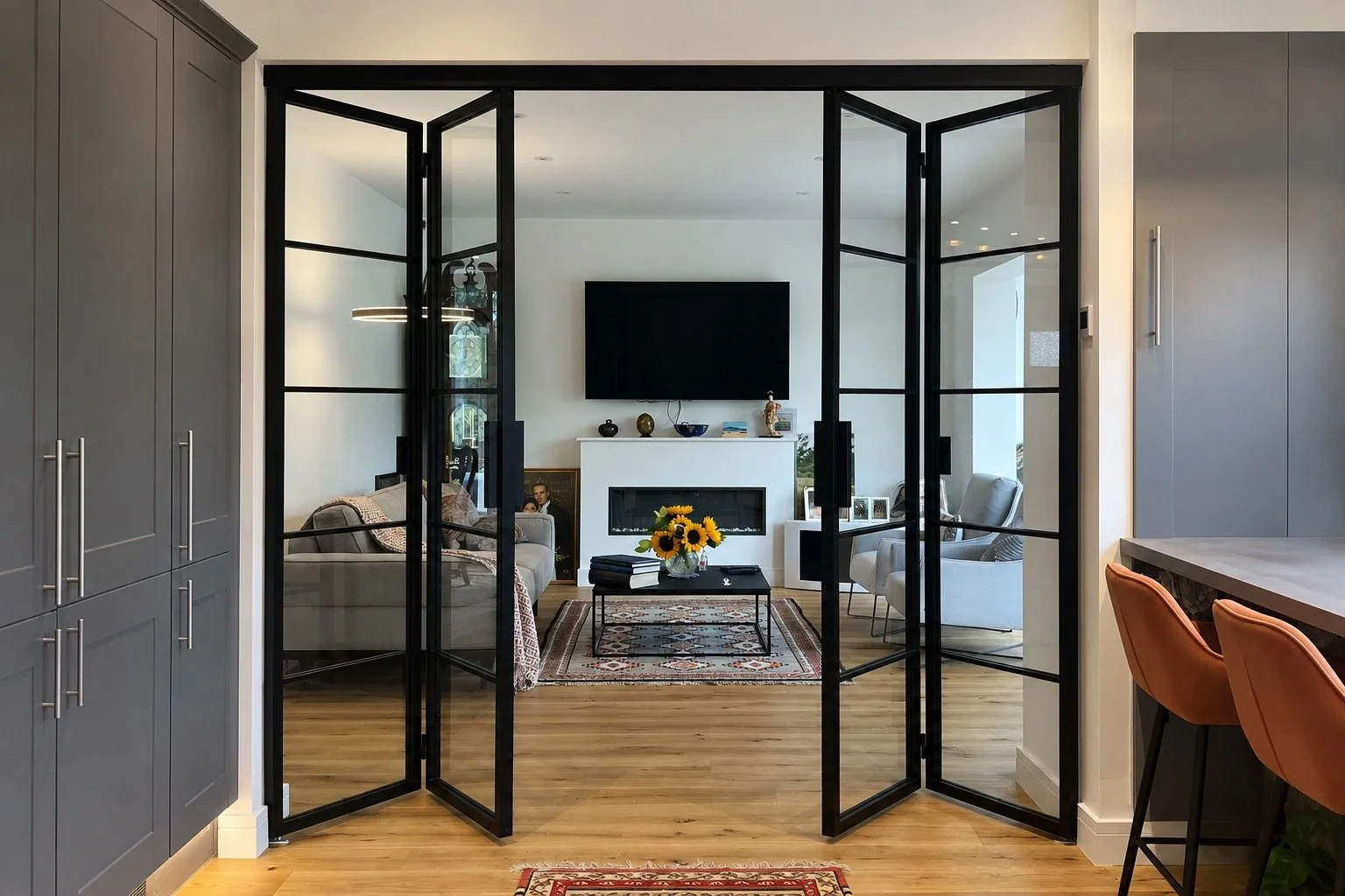 Bespoke steel internal bi-folding doors fully open between two adjoining rooms in a luxury home by Joshua James.