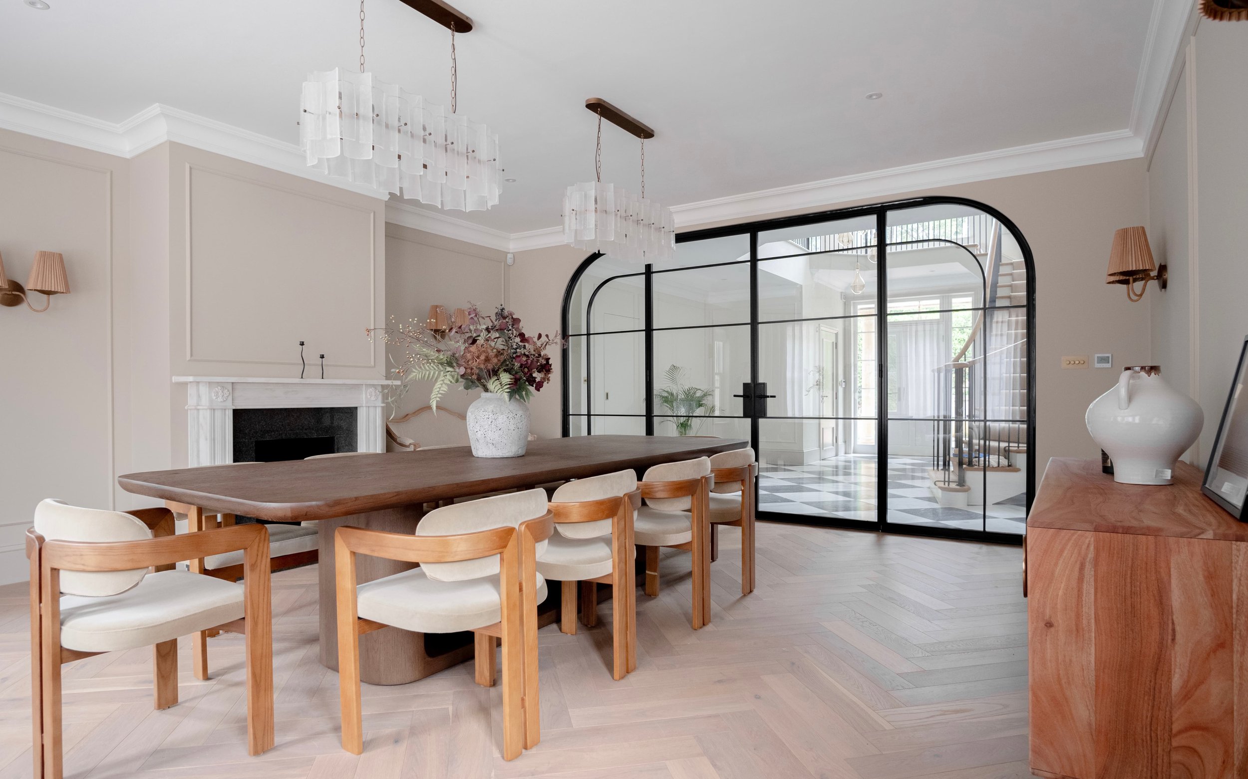 Bespoke InoCross20FR arched steel-framed fire-rated double doors with curved fixed side screens, separating an elegant dining room from a grand entrance hallway.