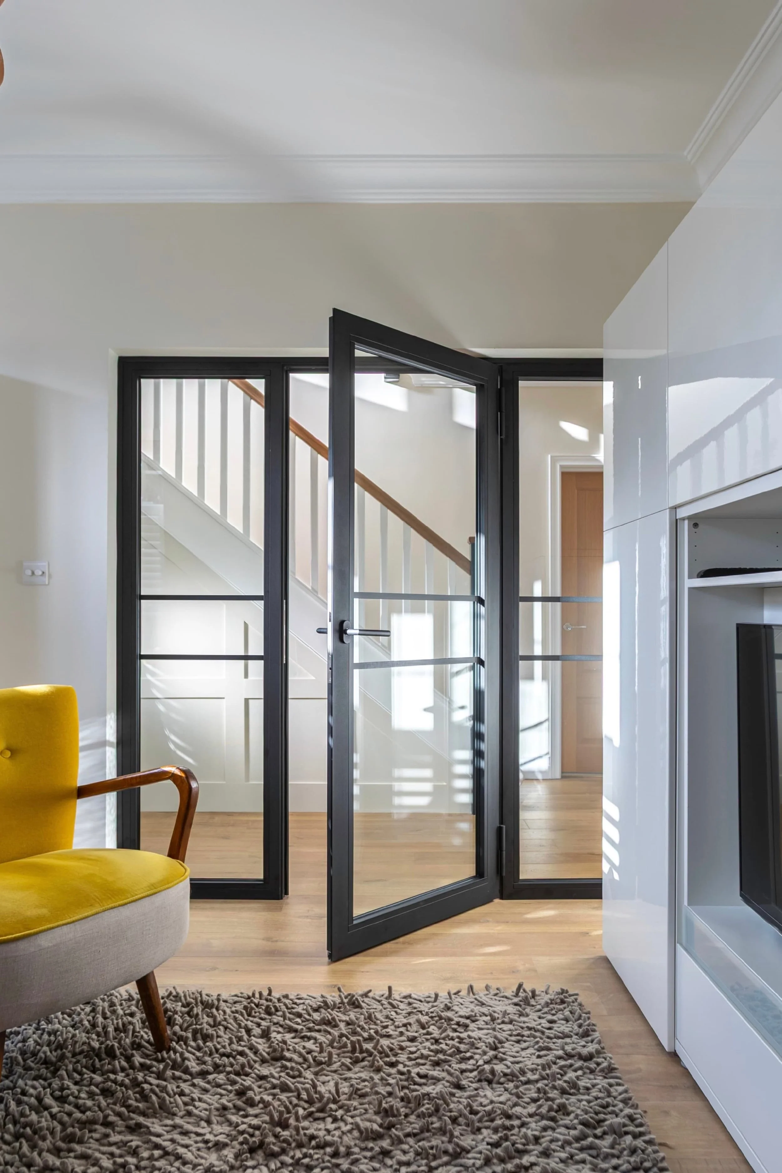Open fire-rated steel door with side screens showing transition between hallway and living room.