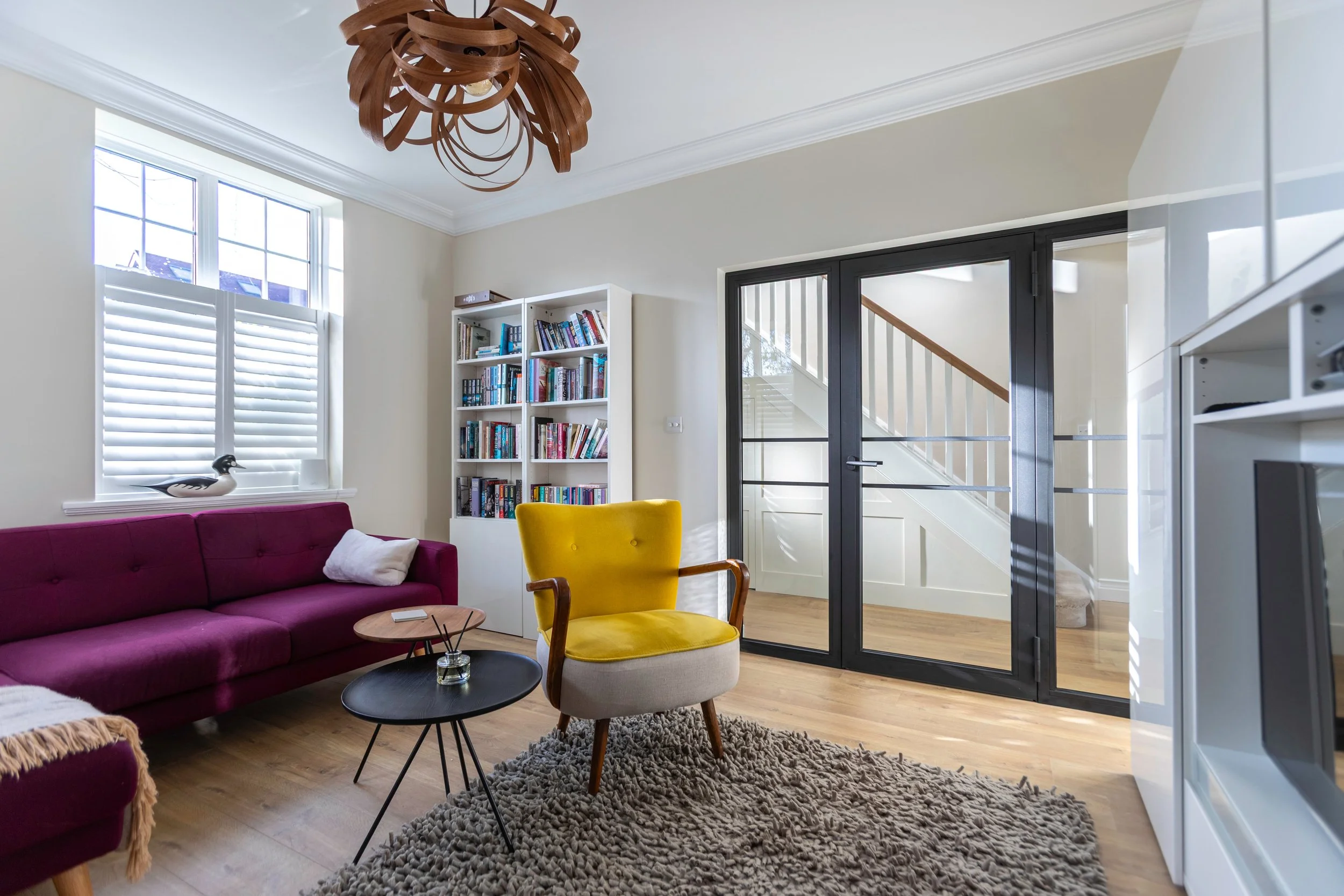 Internal steel doors bringing natural light into a hallway from an adjoining living room.