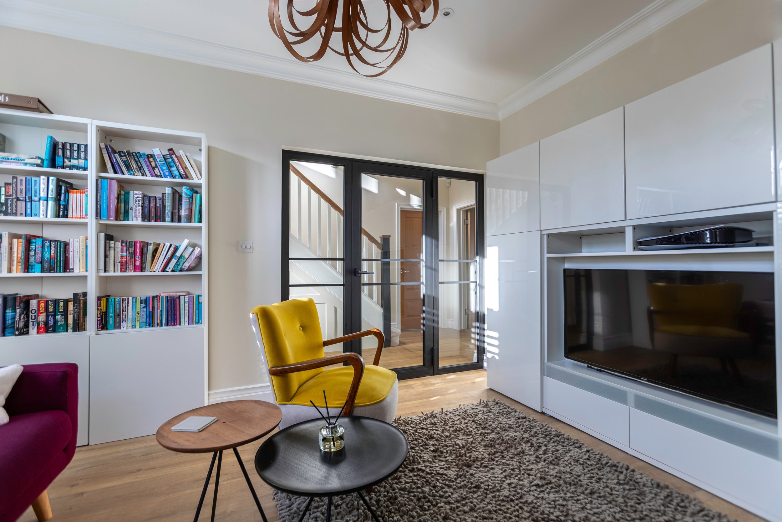 Black steel partition allowing light between hallway and living areas in a luxury home.
