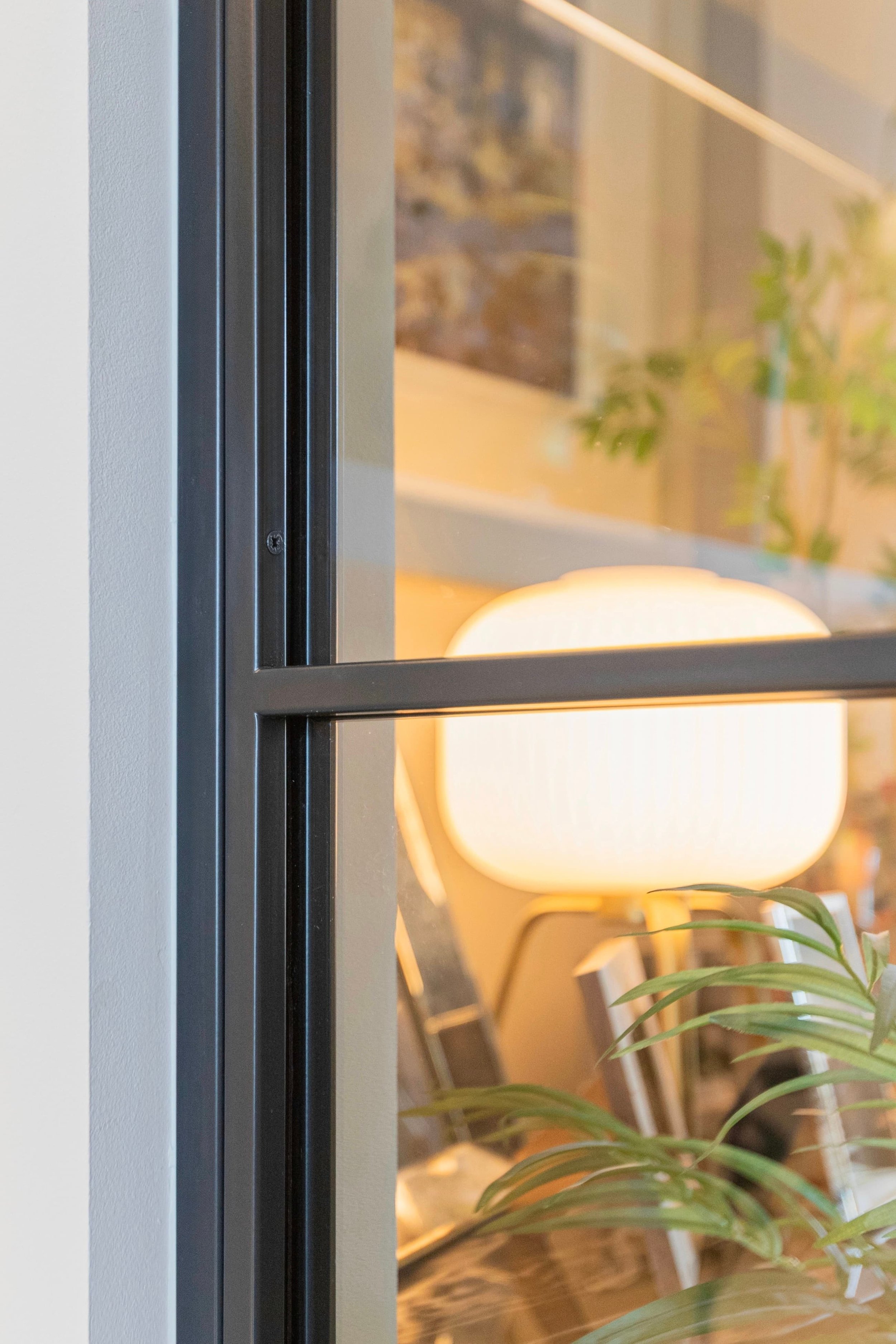 Close-up detail of a black steel sliding door frame with slim glazing bars in a contemporary living space.