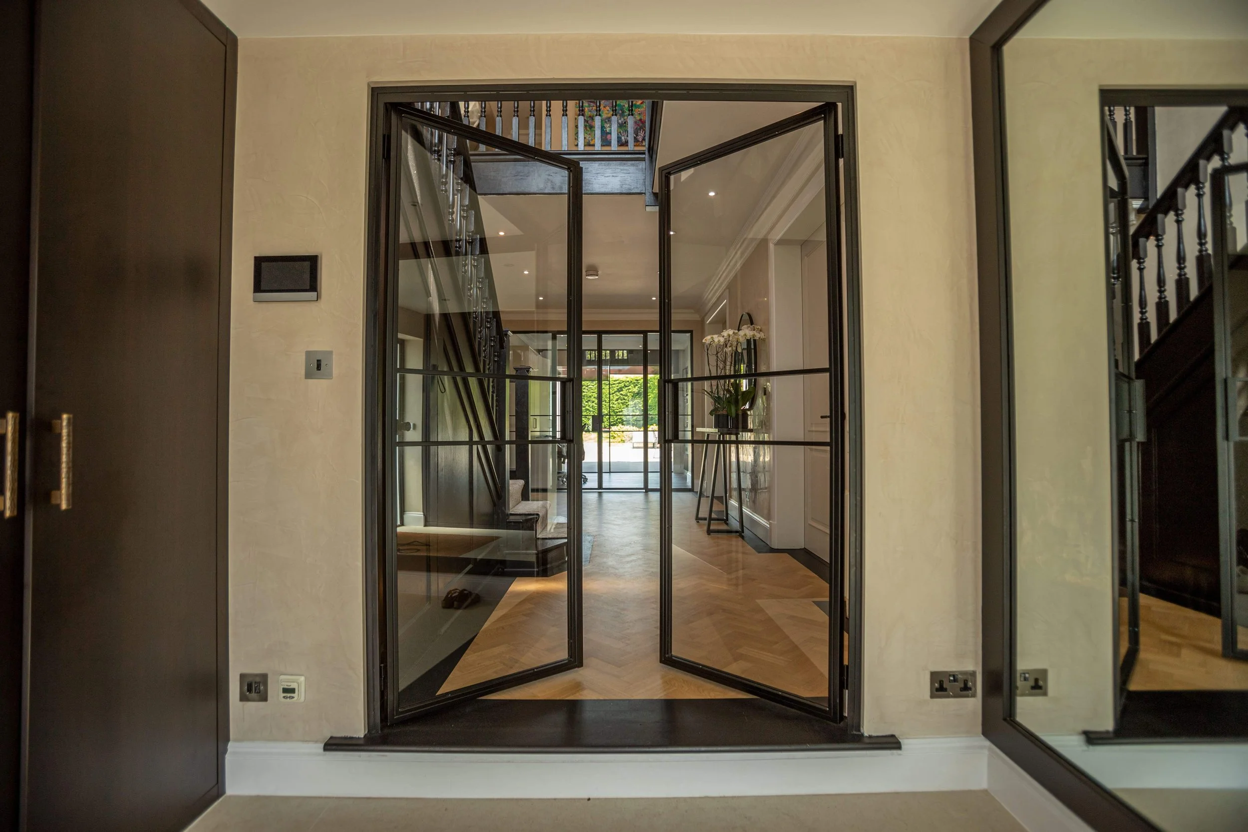 A centrally aligned steel double door set viewed from a hallway, perfectly symmetrical within the opening and aligned with ceiling details