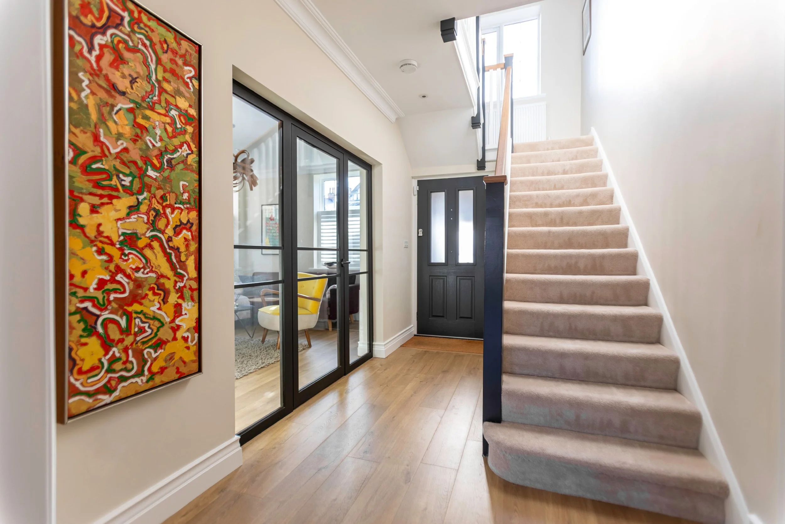 Black internal fire-rated steel door with side screens creating light-filled division in modern living room.