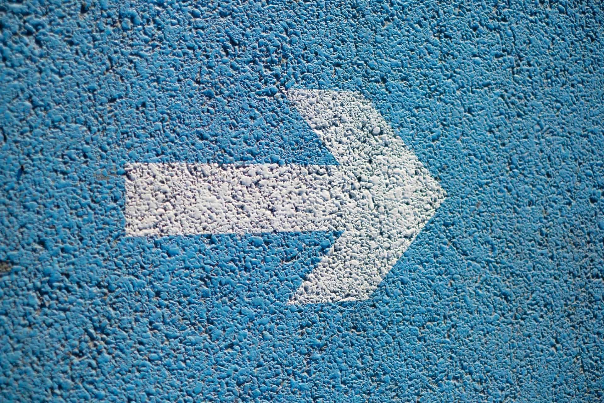 white arrow painted on blue background
