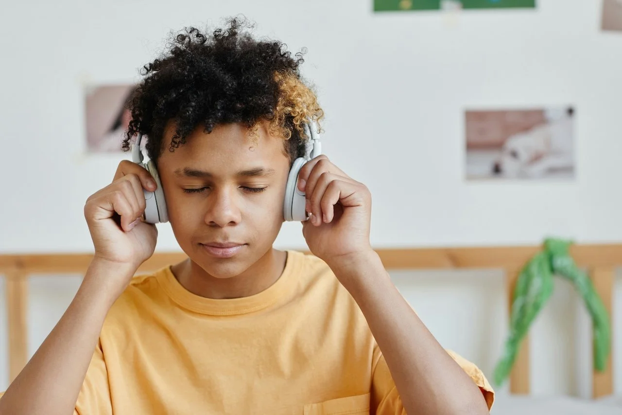 Autistic teen boy in yellow t-shirt wearing headphones