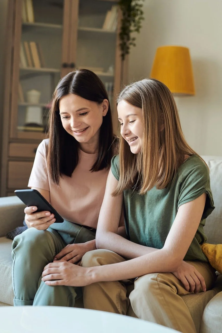 Mom and teen daughter smiling looking at phone