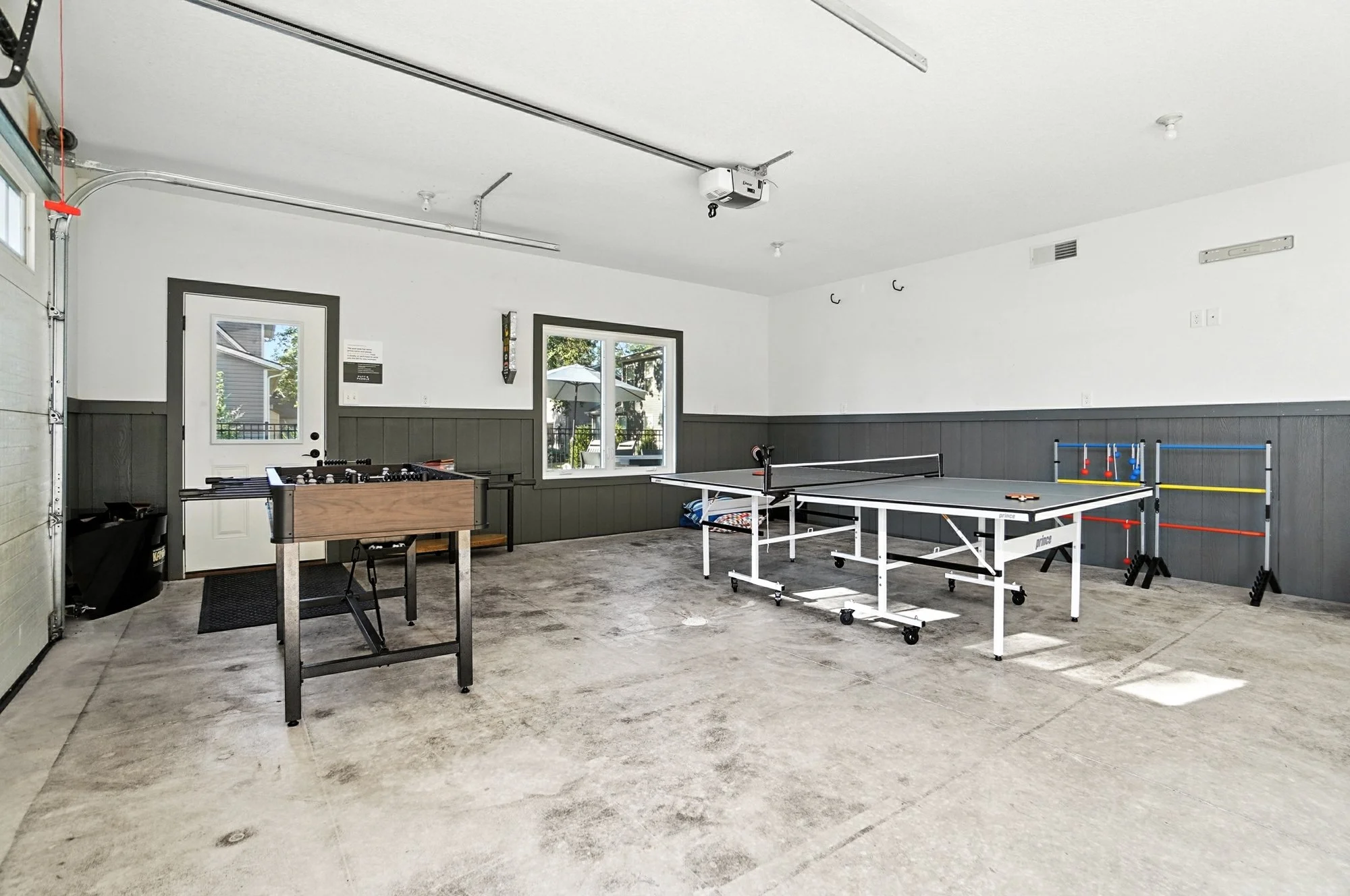 Garage with a ping pong table, foosball table, and yard games.