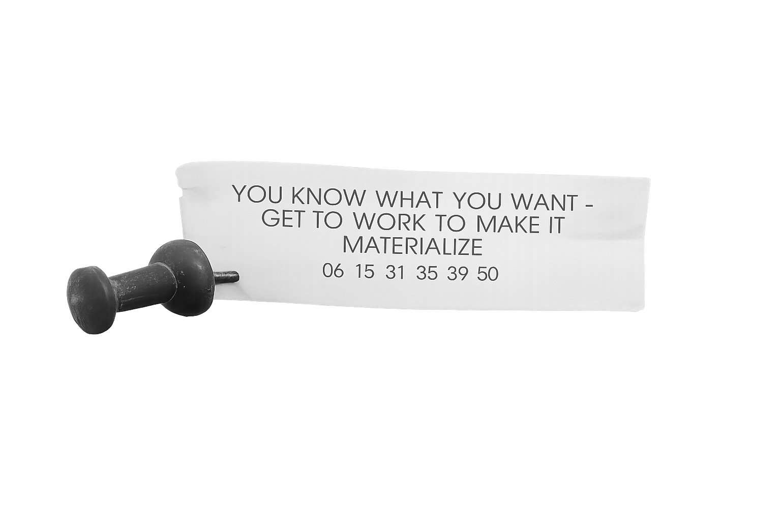 A black rubber stamp and a white paper with the text: 'You know what you want - get to work to make it materialize' and a series of numbers below.