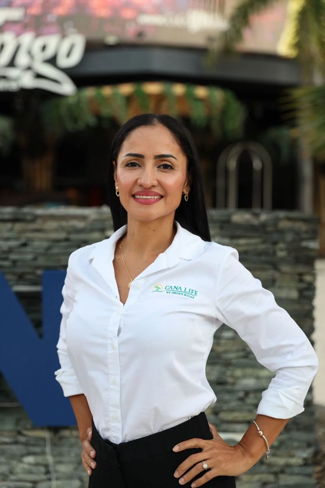 A woman with shoulder-length black hair and light skin, wearing a floral patterned blouse, smiling at the camera.