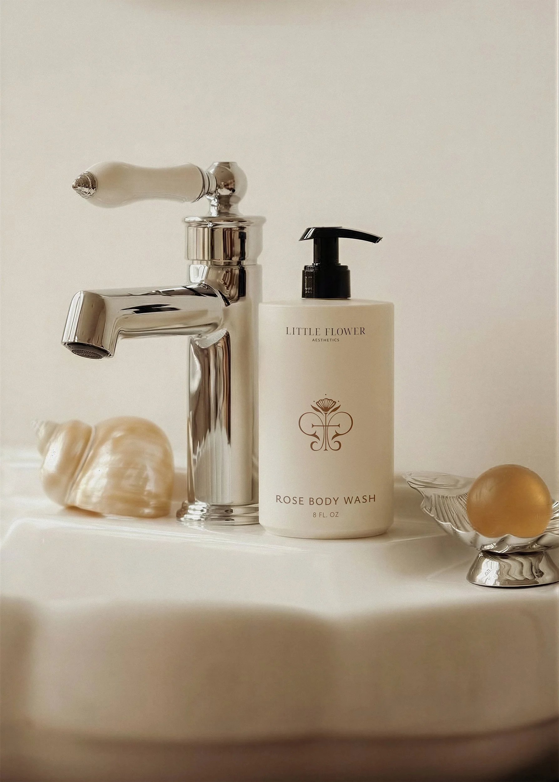 Mockup of Little Flower Aesthetics logomark and typography on a pump bottle on an elegant white and silver sink