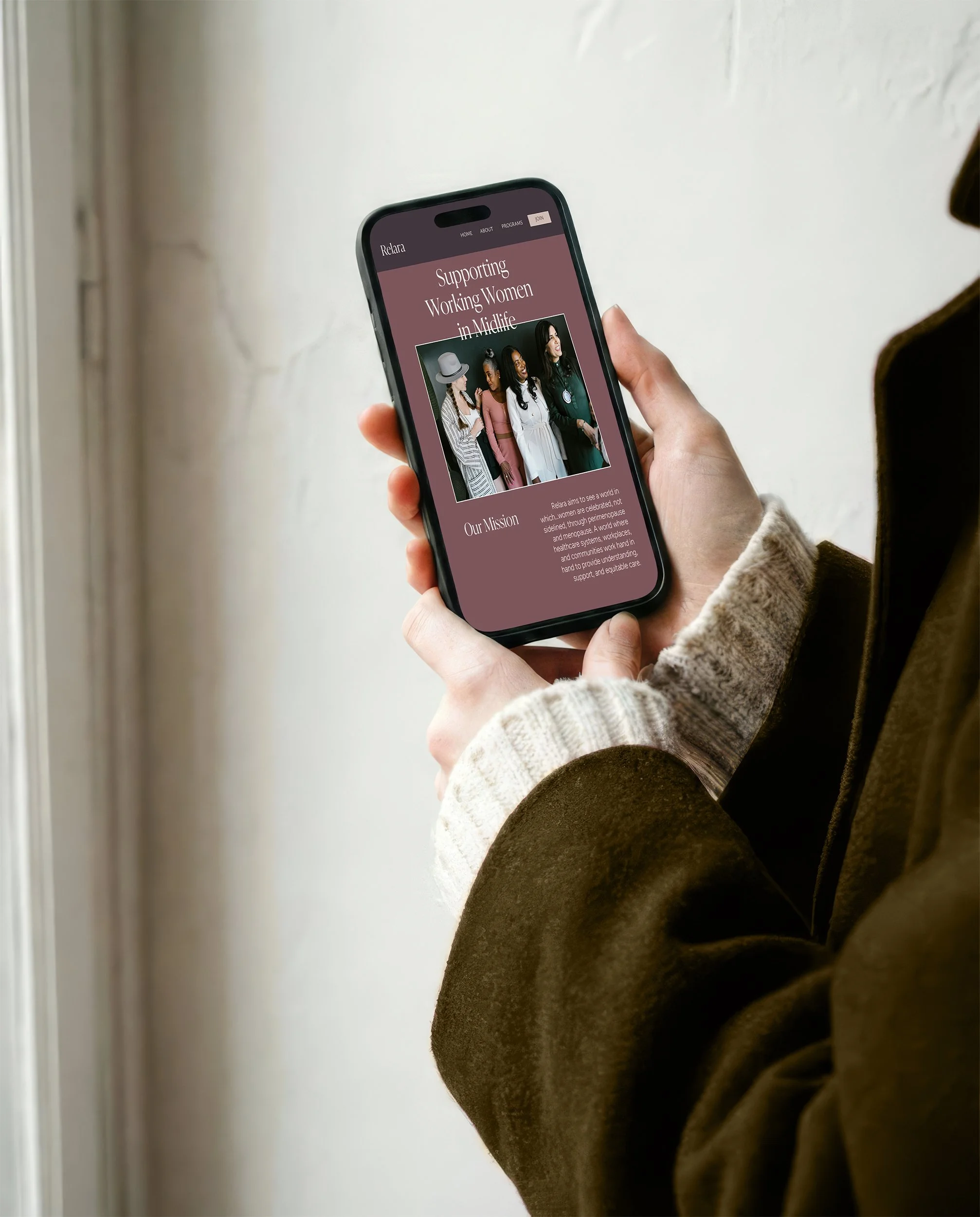 Image of a woman's hands holding an iPhone with a mockup of what Relara's website could look like.