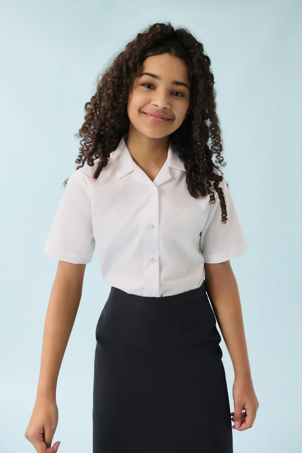 A smiling pupil in a white short-sleeved blouse and navy skirt