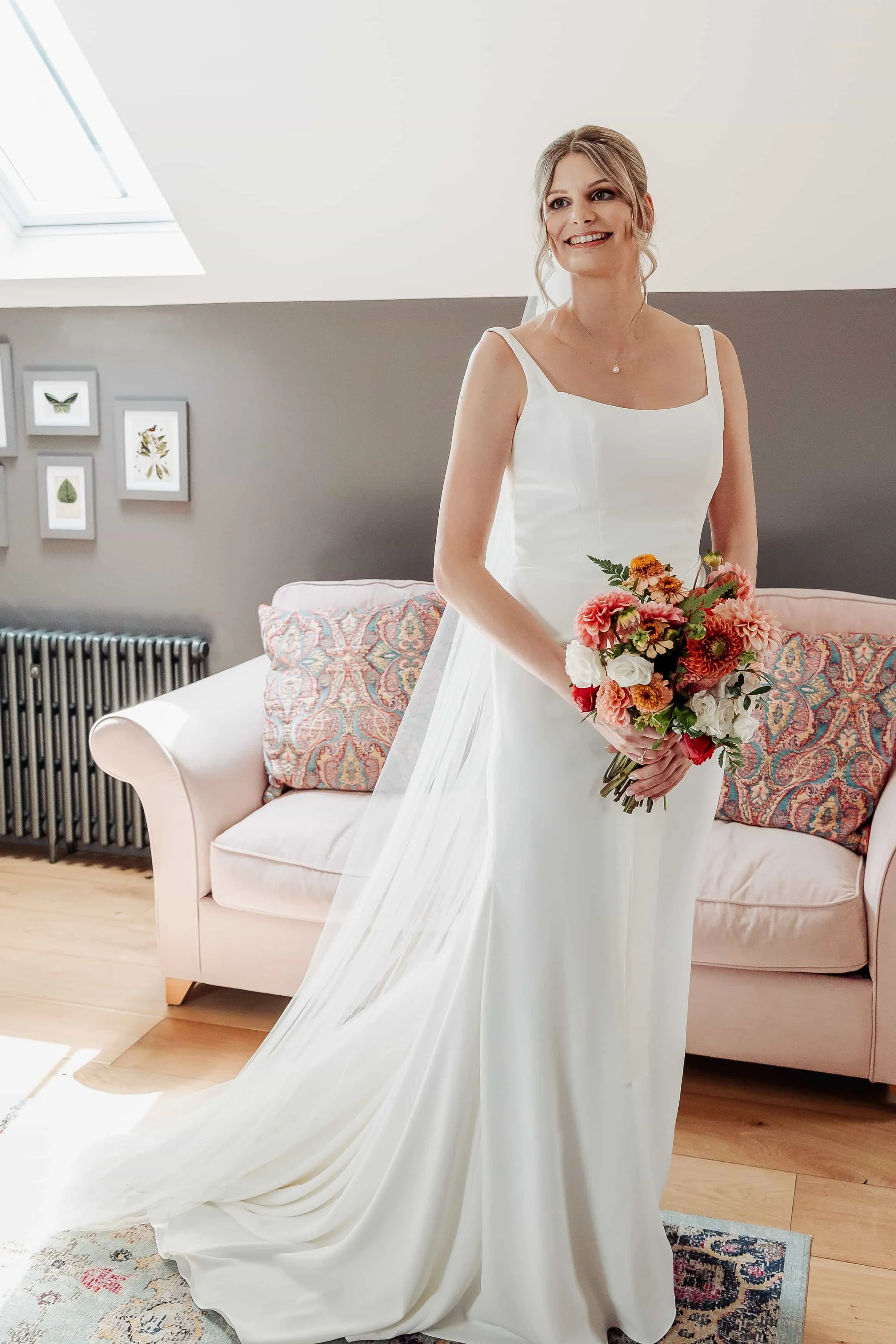 Bride smiling in her wedding dress holding a peach and white bouquet