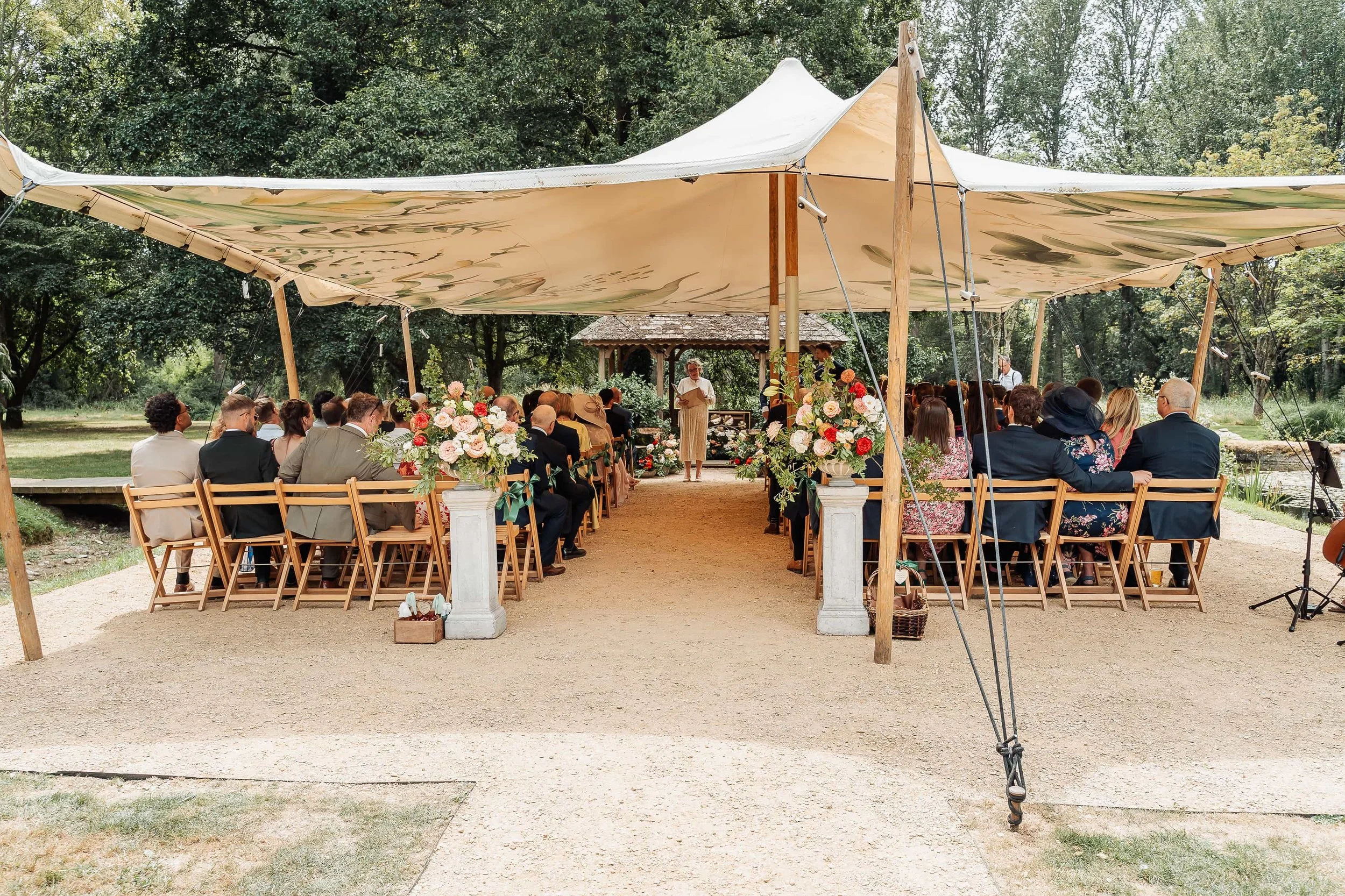 Guests seated under a stretch tent for an outdoor wedding ceremony at The Waters Edge at Ewen