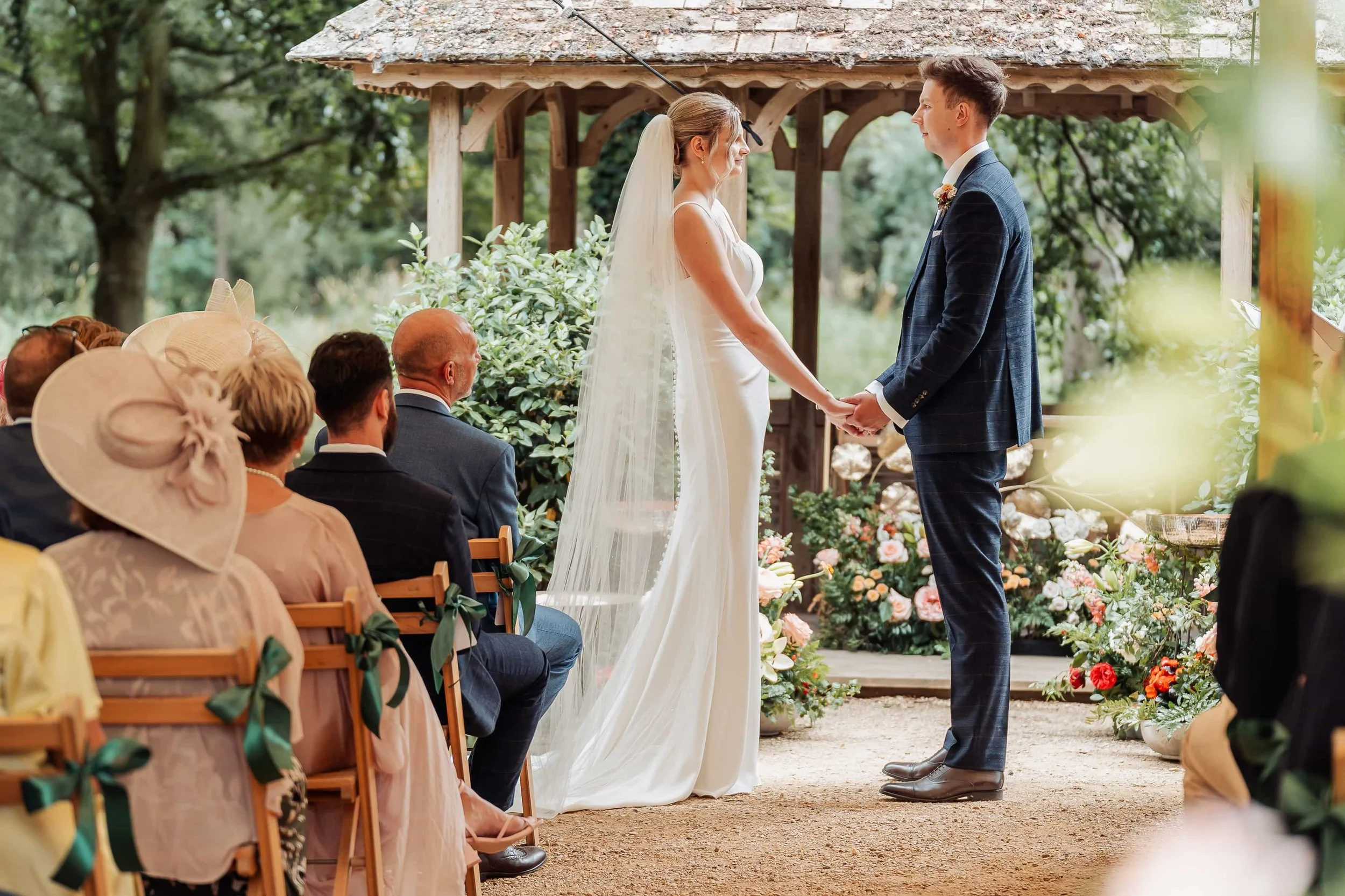 Bride and groom holding hands during their outdoor wedding ceremony at a wooden gazebo