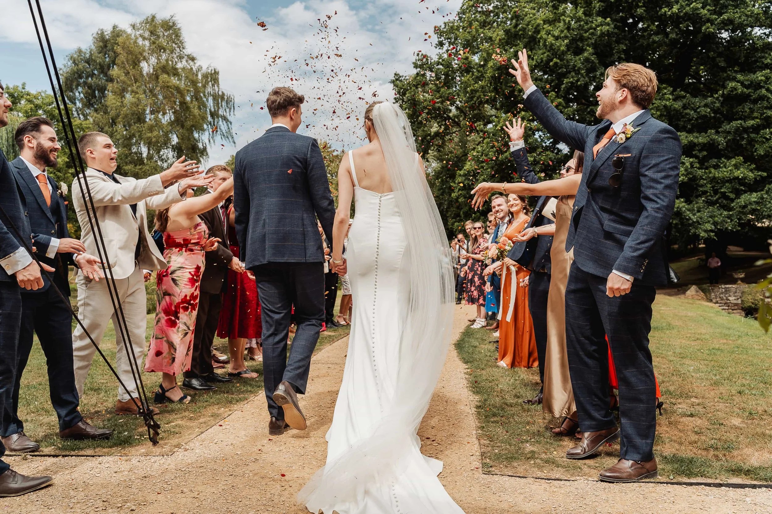 Bride and groom walking through confetti thrown by wedding guests