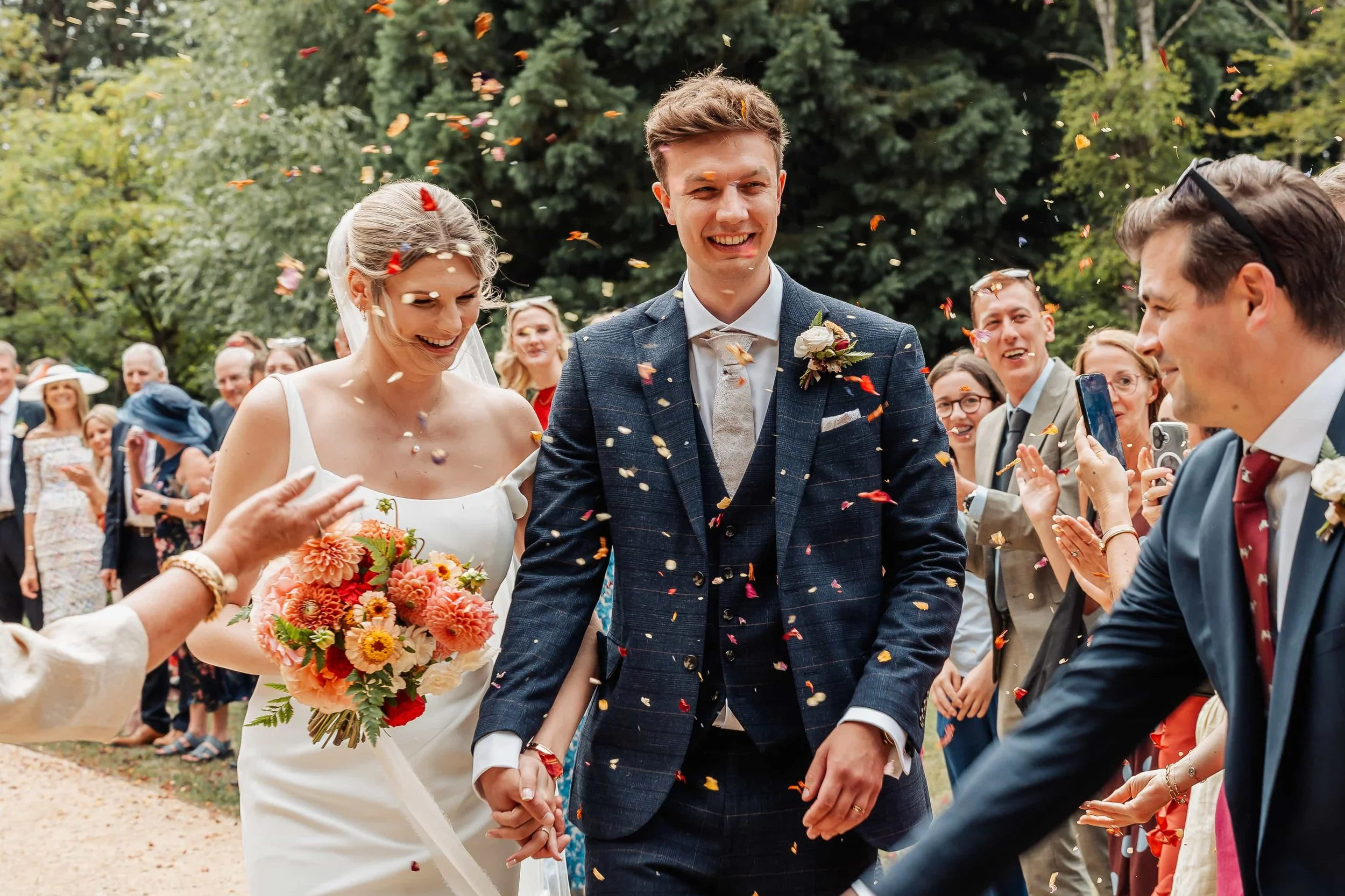 Close-up of bride and groom laughing as confetti falls around them