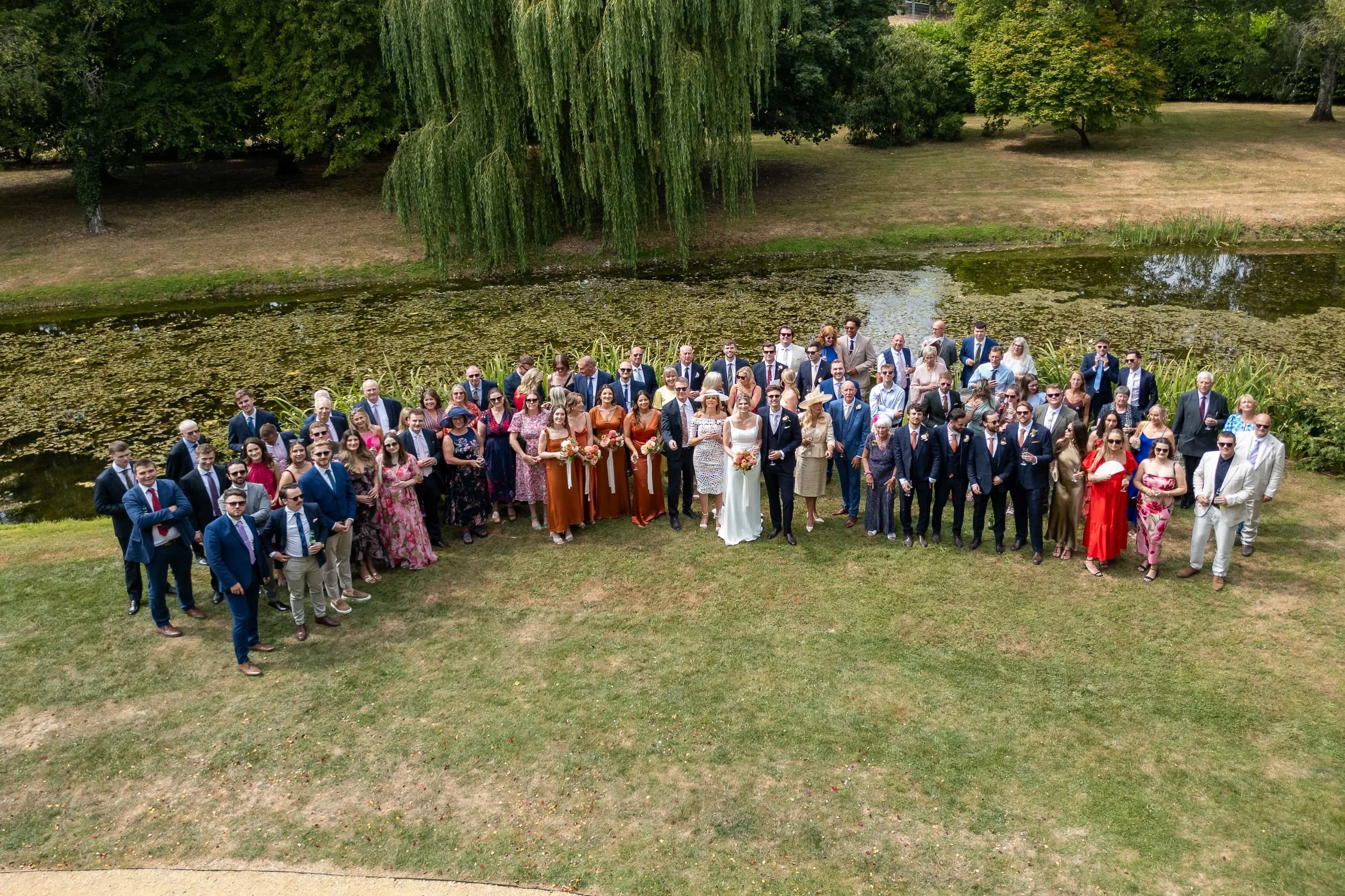 Aerial drone photo of the full wedding party and guests beside the lily pond at The Waters Edge at Ewen