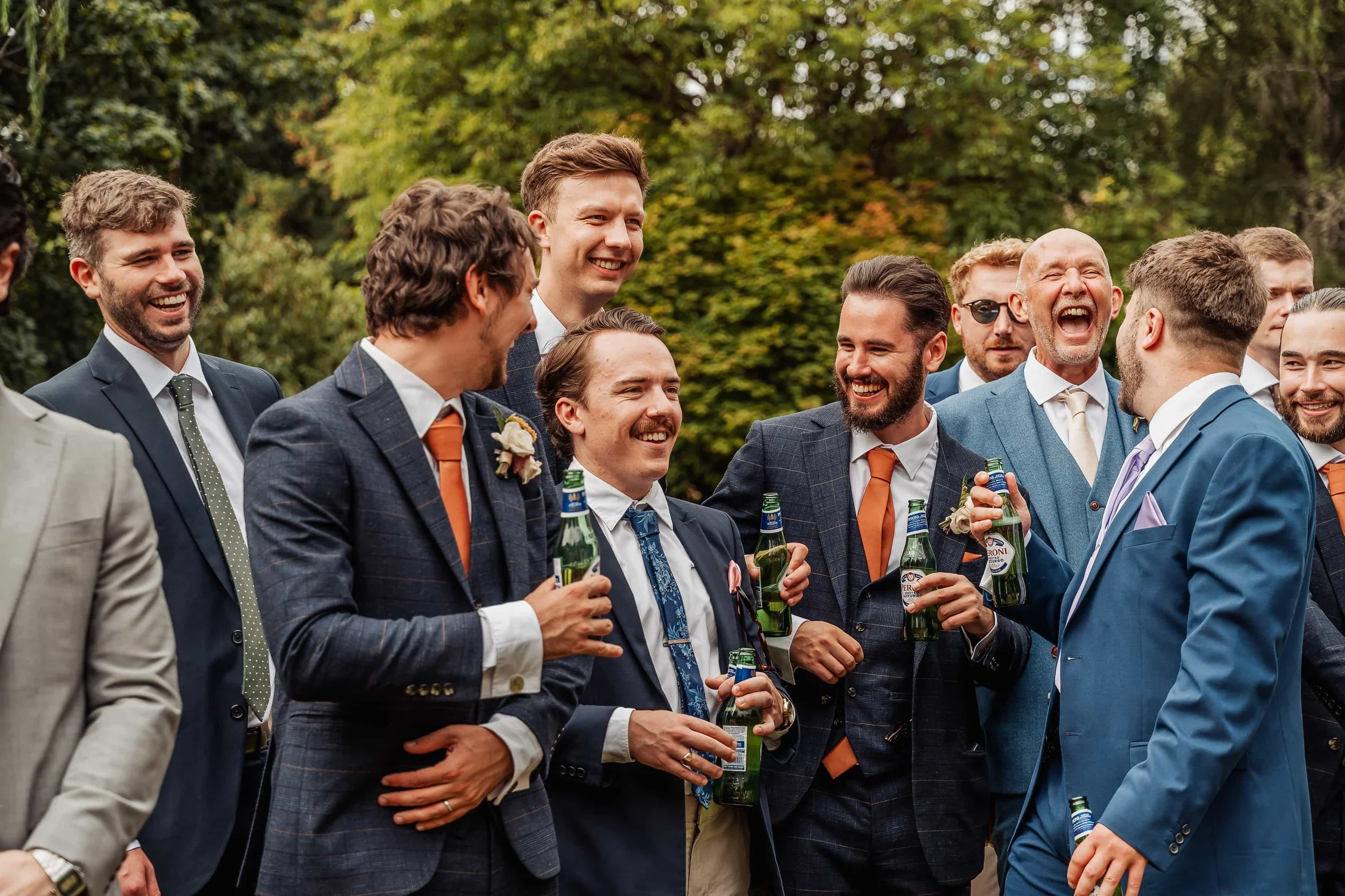 Groomsmen laughing together with drinks at a Cotswolds wedding reception