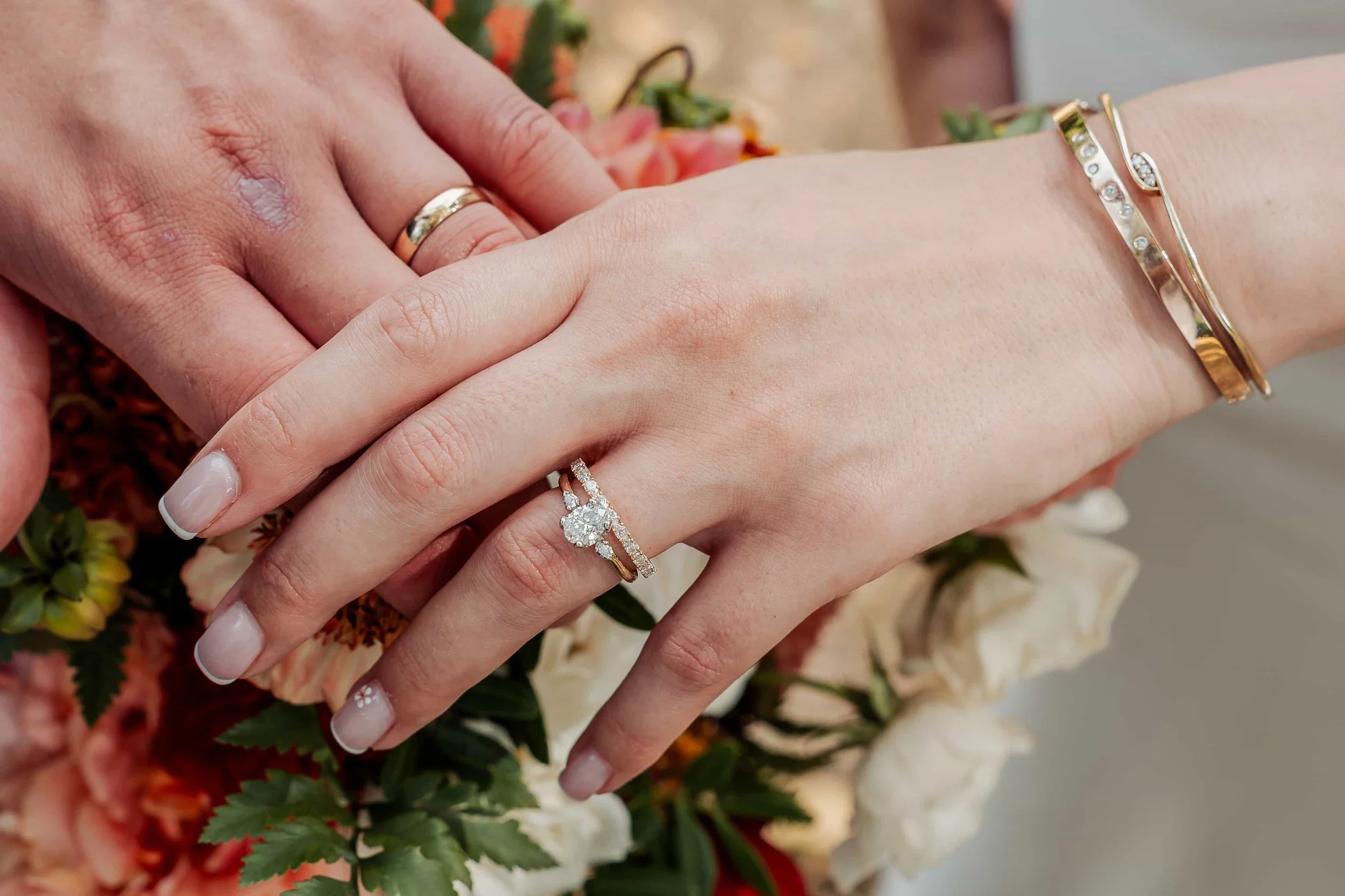 Close-up detail shot of wedding rings resting on a bride's hand with a bouquet