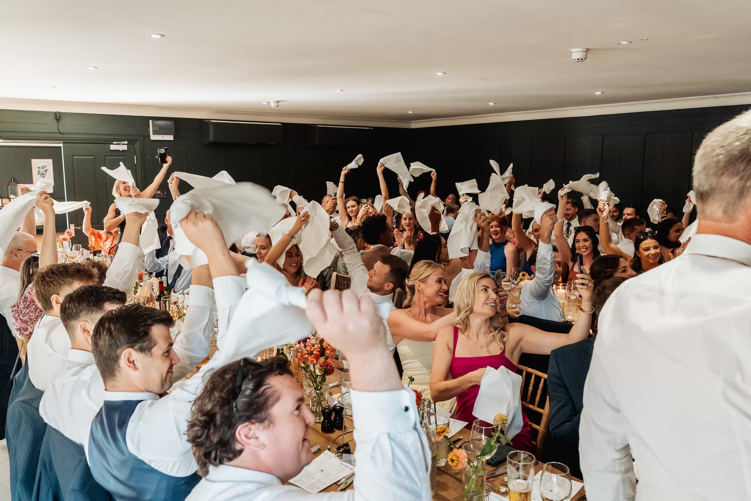 Wedding guests waving white napkins above their heads during the reception celebration