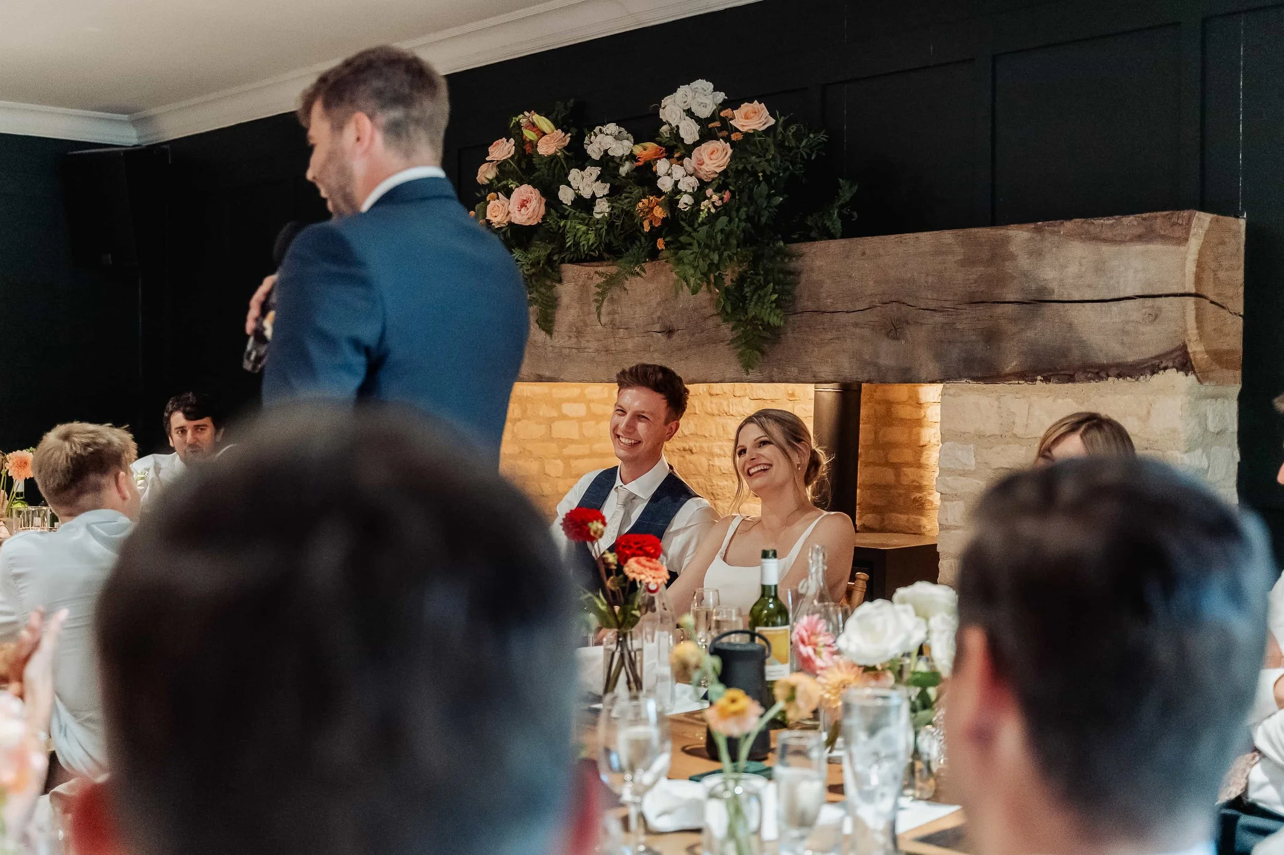 Bride and groom laughing together during wedding speeches at their reception