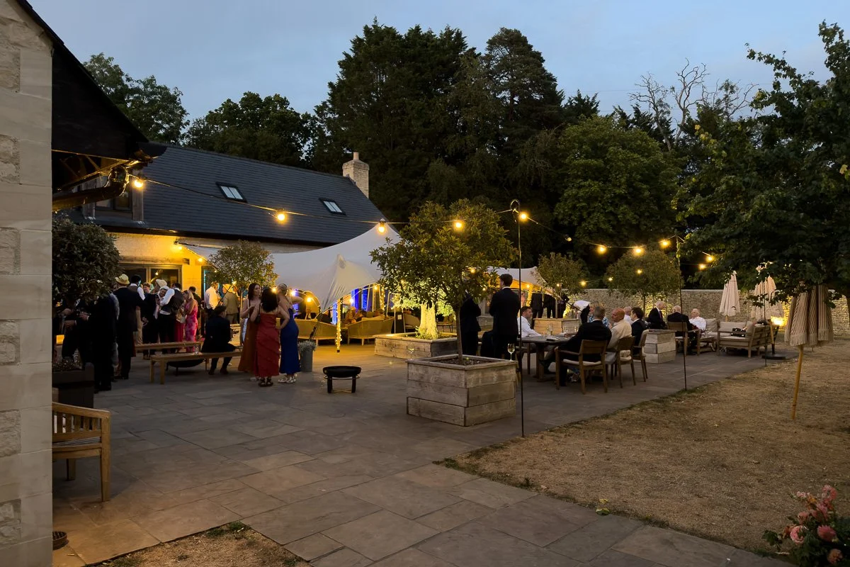 summers evening outside with guests on patio garden lit with subtle outdoor lighting