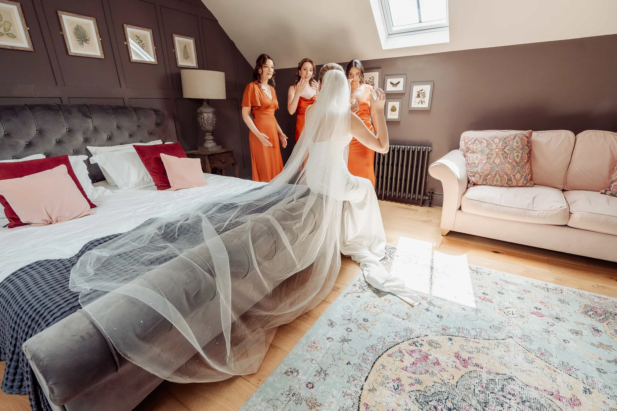 bride sat on bed with wedding veil outstretched behind her